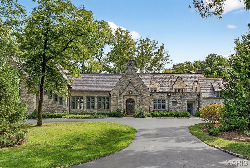 This magnificent English manor evokes the charm of the European countryside, privately nestled on more than 2.8 secluded acres with over 8,000 square feet of refined living space. Originally crafted in 1930 and fully reimagined through a comprehensive renovation between 2013-2017, the residence marries timeless architecture with modern sophistication. Arched doorways, leaded-glass windows, carved millwork, and timbered cathedral ceilings celebrate the home’s historic character, while thoughtful updates include HVAC, electrical, plumbing, and a slate roof. The expansive floor plan features five bedrooms, eleven baths, and a three-car garage, complemented by elegant gathering spaces designed for effortless entertaining.
In 2020, the estate was enhanced by the purchase of an additional 1.3 acres, transforming the grounds into a private resort with a gunite pool, 12-person spa, stone courtyards, fountains, waterfalls, and fire features. An attached pool house—complete with a custom cabinetry, a farm sink, and beverage drawers—perfectly completes the retreat. Privately situated yet walkable to John Burroughs School, Reed Elementary, and St. Louis Country Club, this is a truly rare offering in the heart of Ladue.