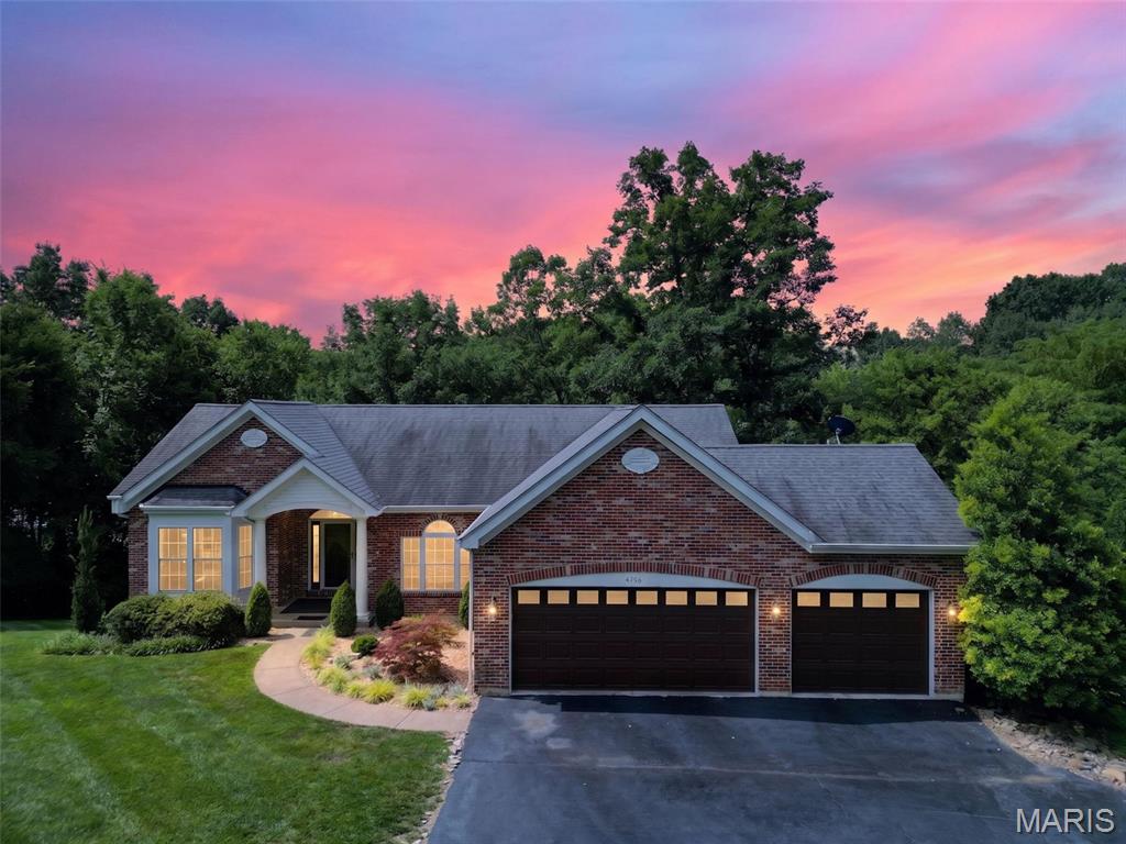 Welcome to this exceptional luxury ranch offering over 2850 square feet of beautifully designed living space on more than 1 acre of wooded ground backing to a stocked lake. This impressive 4 bedroom, 3 full bath home features hardwood flooring, vaulted and coffered ceilings, and an open floor plan filled with natural light. The entry foyer opens to the office, living room and dining room. The office features a bay window, while the living room showcases a wall of windows with breathtaking views of the mature trees and lake. The dining room offers hardwood flooring, crown molding, transom window and arched openings. The kitchen boasts 42 inch cabinets with crown molding, granite countertops, tile backsplash, breakfast bar and ceramic tile flooring. Main floor laundry includes a utility sink and additional storage. The private primary suite features a coffered ceiling, ceiling fan, atrium door leading to a private deck overlooking the lake, and a luxurious en suite bath with double vanities, jetted soaking tub and step in shower. Bedroom 2 includes hardwood flooring, ceiling fan and deck access. The partially finished walk out lower level offers a spacious family room with LVP flooring, 2 additional bedrooms, a full bath with step in shower and access to the covered deck and concrete patio, both overlooking the stocked lake. Enjoy outstanding community amenities including an in ground pool, clubhouse, pickleball court, playground and scenic trails. Surrounded by mature trees and offering incredible outdoor living spaces, this remarkable home combines luxury, comfort and breathtaking waterfront views in an unforgettable setting.