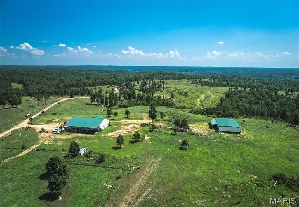 Just 15 minutes southeast of Greenville, this expansive 2,155 +/- acre property offers a rare mix of privacy, functionality, and natural beauty in southeast Missouri. A 25-acre private lake sits at the heart of the property surrounded by open pasture areas, hardwood timber, and scenic views. The farm is well-equipped for livestock, with a fully fenced perimeter consisting of 16.5 miles of 5 strand barbed-wire, approximately 400 acres of cleared ground planted in Kentucky 31, orchard grass, and clover. Three large fenced pastures and nine ponds support rotational grazing, while a smaller woven-wire pasture is ideal for goats, sheep, or weaning calves. Additional infrastructure includes a fenced hay area, two pipe corrals, and a deep 65 GPM well that provides adequate water to the property. A large shop with rustic living quarters overlooks the property from a ridgetop, and a new 60x80 clear span steel barn offers versatile storage or operational space. A cabin and campground sit along the lake’s edge, with several ideal home sites nearby. The land is rich with wildlife, including deer and turkey, and features seasonal creeks, many natural springs, and a well-maintained internal road system that spans the entire tract. Whether for potential ranching, a recreational haven, or building your dream retreat, this property delivers a rare opportunity to own a large, scenic, and highly functional piece of Missouri countryside. Call today to schedule your private showing!