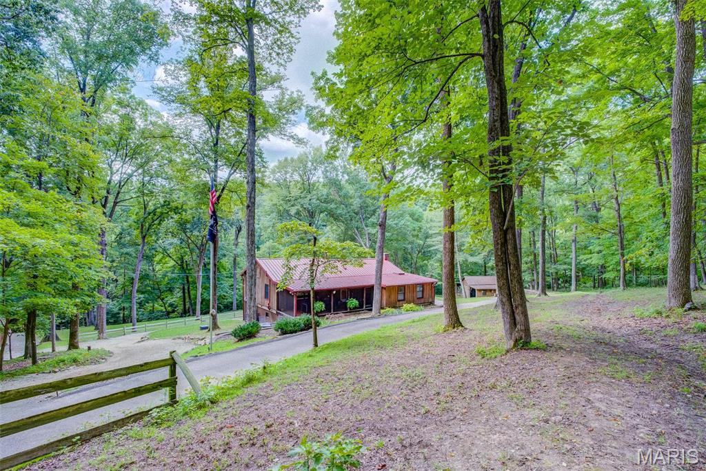 FULLY RENOVATED ranch home that blends rustic charm w/modern luxury nestled on 4+/- acres of serene forested land bordered by a ravine with a separate studio/casita, wood barn and 2-car carport. This retreat has a quiet country feel yet has the convenience of the numerous amenities nearby. The main home’s upper-level boasts hardwood and tile flooring, a large master bedroom w/en-suite bathroom & freestanding tub, guest bathroom, office, mudroom, great room and chef’s kitchen w/14’ butcher block island, custom cabs & high-end applis. The walkout lower level has a second bedroom w/its own private living/entertainment area & bathroom, laundry facilities & a large workshop. Spacious front and rear screened-in porches, BBQ area, floor-to-ceiling wood burning fireplace, and picture windows providing plenty of light & scenic views. The studio/casita is full of charm & is perfect for visiting guests or a second office, & has its own screened in porch, half bath, & living/sleeping areas. NO HOA! Additional Rooms: Mud Room