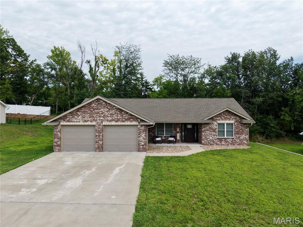 This 4-year-old home offers easy one-level living on a slab foundation with a private backyard backing to woods. Inside, an open concept floor plan connects the living area to an eat-in kitchen featuring granite countertops and plenty of room to gather. The split bedroom design places the primary suite privately apart from two additional bedrooms, with 2 full baths total. The primary suite impresses with a tile shower and a large walk-in closet. A well-appointed laundry room includes a folding counter and cabinetry, plus there's a separate storage/utility closet for extra organization. Low-maintenance, move-in ready, and tucked against a wooded backdrop.