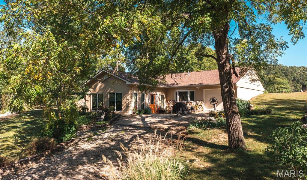 When you drive through the gates & cross the bridge, you are in the shade of mature walnut trees & oaks that line the driveway. The only traffic is wild turkeys or whitetail deer and the occasional bobcat at this Hunter's paradise! The home is a 2,800 sqft earth home w/ a western feel, built w/ efficiency in mind. It has extra insulation, 6 inch walls, a heat pump water heater, Anderson windows, and 2 high energy heat pumps for heat & air conditioning. Interior features of this 3 bedroom, 2-1/2 bath home are granite countertops, new Stove, Microwave, and dishwasher, a Sunroom, & 3 heat sources, new woodwork, new solid wood interior doors, new kitchen cabinets, and crown molding. A new roof was added w/ skylights across the back. The well has a new pump and wiring. Only minutes from town & Ft Leonard Wood. This 102 m/l acre ranch has been used for its capabilities to keep horses over the years w/2 open pastures, a small horse barn & 2 freeze-proof waterers. Also a 40x62 barn w/shop.