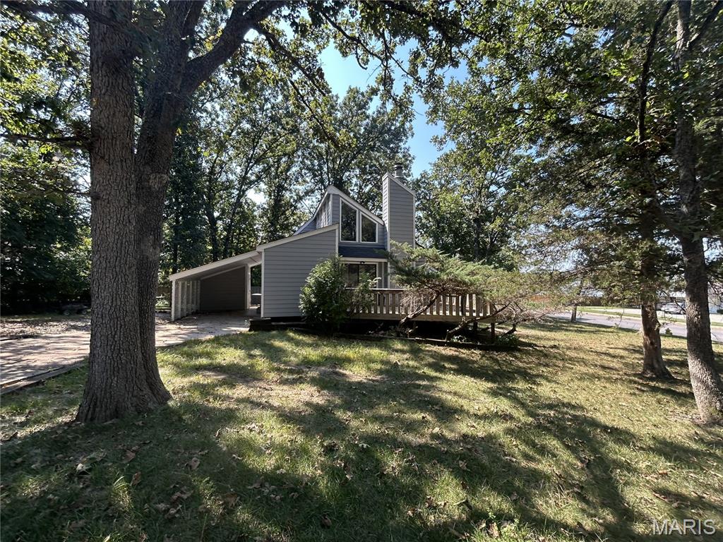Unique character meets comfortable living in this distinctive 3-bedroom, 2-bath custom home! With its mature trees, expansive windows, interesting architectural details, and large deck, this home offers a style you simply don't find in every neighborhood. Inside, you'll find a spacious living area with soaring ceilings, exposed wood beams, and a striking stone fireplace that serves as a natural focal point. The home is in great overall condition and offers a solid foundation for its next owner, while leaving room for some aesthetic updates to make the space truly your own. The main level includes two bedrooms, a full bath, and a versatile sunroom, while the upper level features the private primary suite overlooking the living area. Whether you're drawn to its architectural character or excited about putting your own finishing touches on a one-of-a-kind home, this property offers plenty of potential. Being sold as-is.