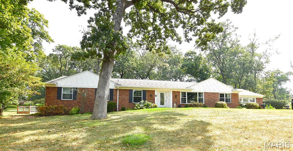 Welcome to Frontenac Forest! This 4-bedroom, 3.5-bathroom home sits on a picturesque one acre lot with mature trees in the Ladue School District. With only three owners, it has been lovingly maintained and thoughtfully updated. The large entry hall shows off the beautiful hardwood floors which flow through most of the main level. A formal dining room, formal living room with rich woodwork overlook the expansive front yard.  A cozy family room with stone fireplace walks out to the patio as well as flows into the kitchen. Here, the focal point is the mature landscaping viewed through the large picture windows. The kitchen also features granite countertops, a center island with dual electric oven/gas range, and a built-in secretary’s desk. A most private patio off the kitchen and family room is surrounded by views of the lush gardens (and tree house!). The natural landscaping offers shady morning coffee and birdwatching. The family room's masonry wood-burning fireplace makes this home ideal for gathering and entertaining. The expansive primary suite offers a sitting room, huge walk-in closet, and a spa-like bath with soaking tub, separate shower, and plenty of vanity space. The finished lower level offers an additional 1000 sf expanding the living space with a full bar, rec room with egress window, 4th bedroom with egress window, full bath, and generous storage. Additional highlights include an updated hall bath, oversized 4-car garage, sprinkler system, central vacuum, main floor laundry, new 6” oversized gutters on the majority of the home, and a new high-efficiency humidifier (installed 2 years ago; HVAC system approx. 15 years old). This is a rare opportunity to own in one of Frontenac’s most sought-after neighborhoods—a timeless home that blends classic craftsmanship, modern updates, and unmatched location. One road in this neighborhood with security cameras at entrance. See indentures on line. Fences are allowed!