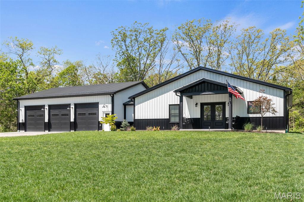 Discover this stunning barndominium home offering 6 acres of tranquility with upscale living. Just 3 years new, this metal frame blends modern elegance with lots of craftsman charm with a double door front entrance. Step inside to find 9 foot ceilings, beautiful engineered wood floors throughout with spectacular lighting and fixtures adorning every space. The heart of the home boasts custom cabinetry, a huge island, and a pantry perfectly complemented by high-end stainless-steel appliances—all just 3 years young, including the refrigerator. The Primary bedroom has your dream bathroom with a walk-in Onyx shower, a soaking tub, and double vanity and a 6x16 walk-in closet. An energy-efficient heat pump ensures comfort year-round, while the oversized main-floor laundry/mudroom adds convenience. Outdoors, enjoy privacy, a covered patio for that morning coffee. The oversized 6-car tandem garage provides ample room for several vehicles, or storage, or workshop or whatever you'd like it to be. The garage has x3 10 foot garage doors.400 AMP. Drop Zone Water Softener. This exquisite home is a rare find—offering privacy, efficiency, and timeless style.