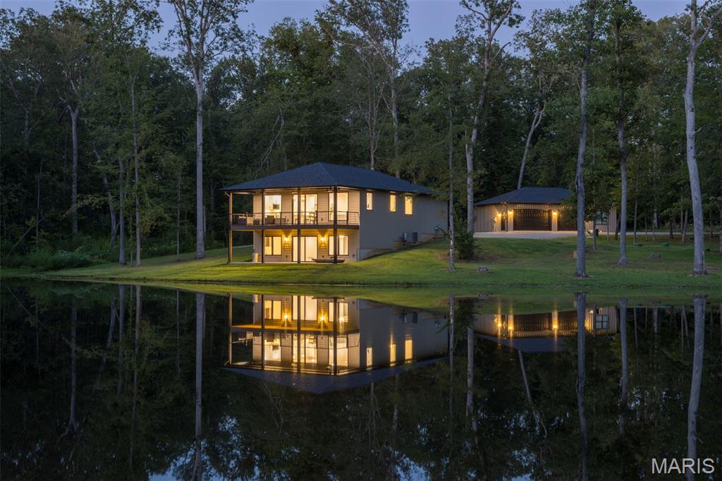 Seclusion, beauty, and craftsmanship rarely come together like this. Completed in 2025, this stunning custom Woodland Cottage is tucked away on 12.36 wooded acres among mature white oaks, overlooking its own approximately 1.6-acre stocked lake—yet sits just minutes from Farmington. From inside the home, the covered deck, or the lake, not a single neighboring home is visible. Large Andersen windows bring the outdoors in and showcase the peaceful lake and woodland views throughout the open-concept living, dining, and kitchen areas. The main level features 9-foot ceilings, a spacious primary suite, guest bedroom, private laundry, custom cabinetry, quartz countertops, an oversized island, and a large electric fireplace.

With approximately 2,780 finished square feet, the home offers 3 bedrooms and 3 full baths, including a beautifully finished walkout lower level with a large family room, third bedroom, office, full bath, abundant storage, and a dedicated theater or multipurpose room. Step outside to a 10' x 32' covered deck or matching lower patio and enjoy the kind of quiet and privacy that is increasingly difficult to find.

The property continues to impress with an oversized, insulated and heated 3-car detached garage plus an approximately 360 sq. ft. private studio apartment complete with its own kitchen, full bath, laundry, separate HVAC, private entrance, and dedicated parking—ideal for guests, extended family, or a private retreat.

Outside, explore the stocked lake with bass, crappie, bluegill, and catfish, raised cedar garden beds, apple, peach and plum trees, and more than 12 acres of your own secluded woodland. Spectrum fiber internet, a private well with water treatment, and no HOA add modern convenience to the country setting. A brand-new luxury home, private lake, wooded acreage, complete seclusion, and quick access to Farmington—3069 Highway OO is truly a one-of-a-kind property.