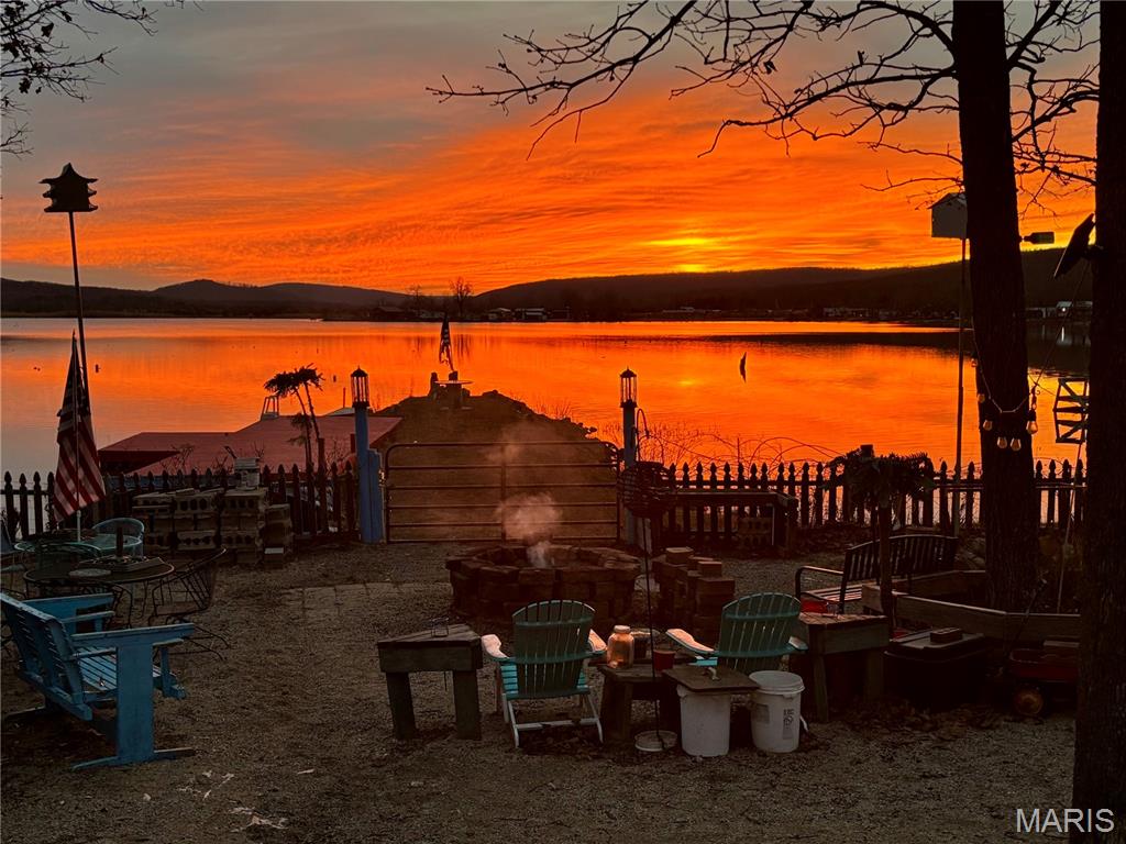 Motivated Sellers! Here's your chance to own an incredible **lakefront retreat** at beautiful Lake Hanna in Ironton, Missouri! Located on a quiet dead-end road, this fenced property includes four lots with direct lake frontage, offering the privacy, space, and recreation you've been searching for. The 16' x 52' cabin features an open living and kitchen area with a cozy wood stove, one bedroom, one bathroom, and washer and dryer hookups. Step through the back door into the screened-in sunroom, currently used as a hot tub room, or relax on the covered back porch while enjoying spectacular sunsets overlooking the lake. Outside, you'll find a 10' x 10' private dock, beach area, playground space, solar-powered entry gate, carport, water shed, and three outbuildings with electric service, providing plenty of room for storage, hobbies, or all your lake and outdoor gear. Beyond the property, Lake Hanna offers something for everyone. Enjoy community playgrounds, shower houses, and one of the area's off-road destinations featuring hundreds of acres of ATV, UTV, and side-by-side trails and mud pits. Spend your days boating, fishing, kayaking, swimming, or simply relaxing on the water. Conveniently located just minutes from both Ironton and Farmington, you'll also be close to popular attractions including Shepherd Mountain Bike Park, Elephant Rocks State Park, Johnson's Shut-Ins State Park, Mark Twain National Forest, and the Black River.
As an added bonus, association fees are already paid through the current year. Whether you're looking for a weekend getaway, vacation property, or full-time lake home, this one checks all the boxes. Don't miss this opportunity—schedule your private showing today!