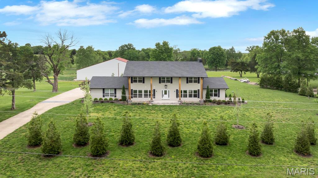 Experience refined country living in this exceptional luxury estate set on 9+ scenic acres complete with a private pond, breathtaking views, and an impressive 88x55outbuilding designed to accommodate hobbies, recreation, business needs and more. Every detail of this custom residence was thoughtfully curated to blend timeless craftsmanship with upscale modern comfort. Inside, the home showcases extraordinary architectural character with soaring ceilings, exposed wood beams, rich flooring, and a stunning floor-to-ceiling stone fireplace that anchors the main living space. The gourmet kitchen is truly magazine-worthy, featuring custom cabinetry, a statement Wolf gas range framed by a custom stone backdrop and artisan wood hood, an oversized island and designer finishes. The open-concept layout was designed for both everyday living and grand-scale entertaining, offering seamless flow between the kitchen, dining, and living areas while capturing picturesque views of the surrounding acreage. Expansive windows flood the home with natural light and bring the outdoors in while you relax or entertain in your large hearth room with its own private entry and bathroom. Retreat to a private luxury primary suite and enjoy the peace and privacy only an estate property can offer - featuring a large walk-in custom closet and a spa inspired bathroom with warm wood cabinetry, polished stone countertops, custom tile work & frameless glass shower.  Finished walk up lower level is ready for your finishing touches to suit your needs with a second stone fireplace, custom stained concrete floors and a half bath. Outdoors, the possibilities are endless — fish by the pond, entertain under the stars, store equipment and toys with ease, or create the ultimate workshop inside the massive outbuilding.  This home has been crafted for style and function and is more than a home — it is a private estate lifestyle offering luxury, space, and versatility rarely found in one property.