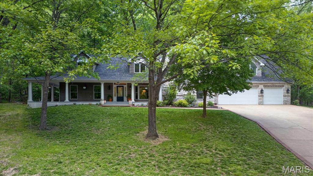 Set on over 3 private acres, this exceptional 1.5 story estate offers a rare blend of refined living and serene, natural surroundings. A picturesque wraparound porch creates a striking first impression, while the backyard unfolds as a true retreat with expansive paver patios, a tranquil koi pond, and cascading waterfall features designed for both quiet moments and elevated entertaining. Inside, rich wood flooring flows throughout the main level, complemented by a formal dining room with a bay window and an inviting living room. The vaulted great room showcases a wood burning fireplace and seamlessly connects to the stunning, thoughtfully designed kitchen. Appointed with granite countertops, a center island with prep sink, double ovens, a newer induction cooktop, two warming drawers, newer dishwasher, built in refrigerator, a beverage chiller, and an adjoining breakfast room, this space is equally suited for everyday living and hosting. A private office just off the kitchen offers both convenience and flexibility. The main level primary suite is a true sanctuary, featuring two walk in closets, and a spa inspired bath with a two person walk in shower, jetted tub, double vanities, and a private commode area with an additional sink. The upper level is equally impressive, offering a large vaulted bonus room, along with four additional bedrooms and two full baths. The finished lower level expands the living space with a rec room, family room, half bath, cedar closet, and generous storage. Additional highlights include a 3 car oversized garage, zoned HVAC, newer roof, central vacuum system, and main level laundry. A truly special offering that combines privacy, scale, and thoughtful design in a setting that feels both peaceful and elevated.