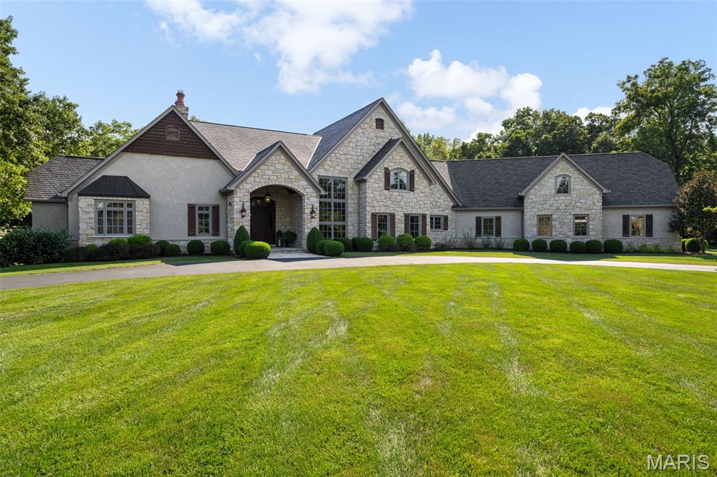 Set amidst 9.93 serene acres, Remington Heights is a private retreat where refined luxury meets the beauty of the outdoors. Thoughtfully designed for both grand entertaining and effortless everyday living, the property offers an exceptional collection of amenities rarely found together in one residence. At the heart of the home, the great room is anchored by a stone fireplace and expansive views overlooking the heated pool and beautifully landscaped grounds. The adjoining dining room is truly one-of-a-kind, featuring an 1859 log cabin originally located in Perryville, Missouri, which was carefully disassembled and re-erected within the home. Multiple fireplaces throughout the residence add warmth and character, including two gas fireplaces and one wood-burning fireplace. The gourmet kitchen combines functionality with timeless style, featuring natural slate tile flooring, granite countertops, a Wolf gas range, double ovens, and premium appliances. A distinctive stone archway connects the kitchen to the great room and its beautifully appointed wet bar, complete with Sub-Zero refrigeration drawers and an ice machine, creating an ideal flow for entertaining. The primary suite offers a private sanctuary with electric shades and a spa-like bath featuring heated floors, a six-foot air bubble tub with heater, and a steam shower with digital multifunction shower heads. The finished lower level provides an exceptional extension of the home's living and entertaining spaces, with a spacious recreation area, second wet bar with Sub-Zero refrigeration drawers and an ice machine, private bedroom, full bathroom, and convenient half bath located just off the pool area. Thoughtfully designed for both entertaining and extended stays, this versatile space offers comfortable accommodations for guests and an inviting setting for gatherings.
The outdoor spaces are designed for year-round enjoyment, with a heated pool, hot tub, waterfall feature, and expansive outdoor living area with an additional outdoor fireplace and partially removable vinyl enclosures. An integrated irrigation system, including drip irrigation for the poolside planters, keeps the grounds beautifully maintained. Technology and infrastructure are seamlessly integrated throughout the property, including a whole-house speaker and TV distribution system, HAI lighting control, security cameras and alarm, geothermal heating and cooling, and an automatic generator providing backup power for the home. Beyond the main living areas, the wooded lower grounds follow the property's creeks and offer a private campsite, fire pit, and flushing toilet, creating an unexpected retreat just steps from home. The property's expansive grounds offer a rare opportunity to embrace a lifestyle defined by privacy, recreation, and connection to nature, all within a remarkably accessible setting. With its exceptional amenities, distinctive architectural character, and beautiful natural surroundings, 3433 Remington Heights offers a truly extraordinary private estate experience. Showings Begin Sept 8th.
