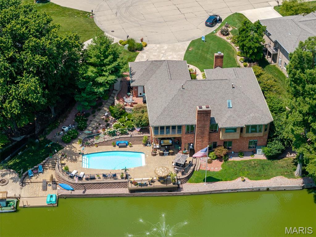 Enjoy the LAKE views from this custom one story with an open floorplan. This home is an Entertainers Dream! The entry Foyer greets you with a vaulted ceiling and Wood floors that flow into the nearby Office with fireplace, and the spacious Dining room with crown molding and plantation shutters. The vaulted Great room features beautiful slate floors and a brick surround gas fireplace. The gourmet Kitchen has new stainless appliances, an abundance of white cabinets, a large island, built-in breakfast area and slate floors. The nearby screened Porch has a fantastic view of the lake and morning sunrises, and overlooks the lush landscaping. The Primary Bedroom features wood flooring, a bay window and 2 walk-in closets, one is from the adjacent Bedroom that is converted to a huge walk-in closet and could double as a nursery with french doors. The private ensuite Bath boasts a whirlpool tub overlooking the lake, a double vanity, walk-in shower, vaulted ceiling and skylight. The additional Bedrooms have wood floors and are spacious. Full Bathroom in the hall is updated easily accessible to guests. The walkout Lower Level has a huge Family room, bamboo wood floors, brick surround fireplace and an amazing Wetbar with concrete top and tile backsplash. There are also 2 Bedrooms, an Exercise room, an updated Bathroom with beautiful tile, a party prep room, and a Wine cellar. All of this space opens to the private pool surrounded by ample patio space for lounging and dining, overlooks the lake and includes a dock, pontoon boat, paddle boat, kayak, and sandy beach area with firepit. This is your own staycation resort! Other extras include lots of storage, a 2nd laundry area, Andersen casement windows. Finished 3 car garage, 2 doggie doors.