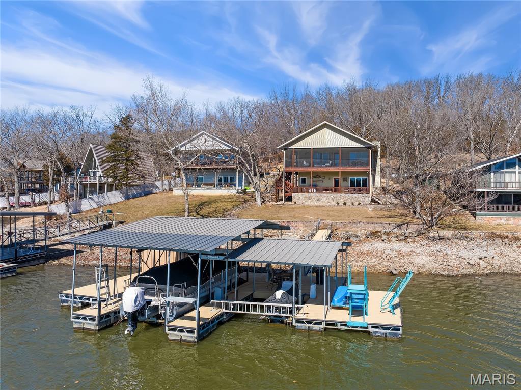 Must see, updated 3-bed, 2-bath lakefront home at the 49MM in Coffman Bend area  close to the  main channel with in a protected cove setting. Recent improvements include new HVAC and roof (2024), water softener (2023), and exterior paint (2025). Layout makes great use of space with two living areas, an impressive kitchen offering ample cabinetry and workspace. Downstairs, the mechanical/laundry room provides a tremendous amount of storage — something often lacking in lake homes. Outdoor space is a major feature here...screened deck on the main level overlooking the water, walkout lower level to a covered concrete patio, plus additional open deck space to the side that’s ideal for grilling, chilling, and firepit area. The lakeside yard offers a moderate slope — usable, comfortable, and just steps down to the dock. Private 75 ft of lakefront with concrete seawall and a large covered dock featuring two slips (10x32 & 10x14), boat lift included, PWC slip with one lift included, swim platform, ladder, and dock storage with refrigerator. Nightly rentals allowed. Private well, septic, Co-Mo internet. Close by water to Red Fox Bar & Grill and Big Dick’s Halfway Inn, with blacktop access by land. Solid lake package!