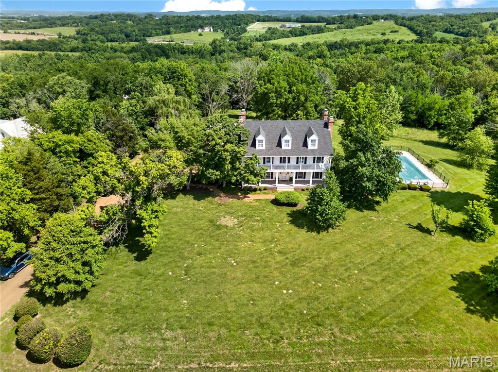 Timeless Elegance Meets Modern Living — A Masterpiece of Craftsmanship and Design
perched majestically atop a hill, this extraordinary residence offers panoramic views that greet you at every turn and a facade that stops you in your tracks. Designed with an artful reverence for historical architecture, this home was custom-built to honor the details of a bygone era while delivering every comfort of contemporary living. The sweeping double front porch, accessible directly from two upstairs bedrooms, sets the tone for a home that was conceived for gracious living. Whether savoring a quiet morning with coffee in hand or watching the seasons paint the landscape below, this porch becomes an extension of your soul. Step inside to discover a foyer where rich parquet hardwood floors and soaring millwork announce that this is no ordinary home. Every wall, every archway, every molding tells the story of local artisans who poured their skill and pride into every detail — from the exquisitely paneled dining room with its arched built-in display niches and dramatic fireplace, to the staircase that rises with effortless elegance. Six fireplaces warm the home both literally and figuratively, including a generous hearth in the kitchen that transforms winter mornings into something worth lingering over. The kitchen itself is spacious and functional, with a large central island, warm wood cabinetry, and a sunny breakfast area that makes everyday living feel like an occasion. 
For the warmer months, a large screened porch invites al fresco dining and evening entertaining in complete comfort, while a private patio and a beautifully situated pool make the most of the elevated setting and the sweeping views beyond — the kind of outdoor experience that makes coming home feel like a getaway. The creative spirit is well served here. A dedicated art studio, flooded with the quality of natural light that serious artists spend their careers chasing, offers an inspiring retreat for painters, sculptors, or anyone who needs a beautiful space to think. A detached second garage presents limitless flexibility — with the bones and positioning to become a guest house, a media room, a home office, or a studio of another kind entirely. The lower level has been finished with family joy in mind: a dedicated toy room and a stage for little performers ensure that the youngest members of the household have a world entirely their own.
This is a home that cannot be replicated. It was designed once, built once, and loved — and now it waits for the family whose life is large enough to fill it. This property parcel includes parcel ID#: 0993200003005200. All fireplaces and pool being sold "as-is".