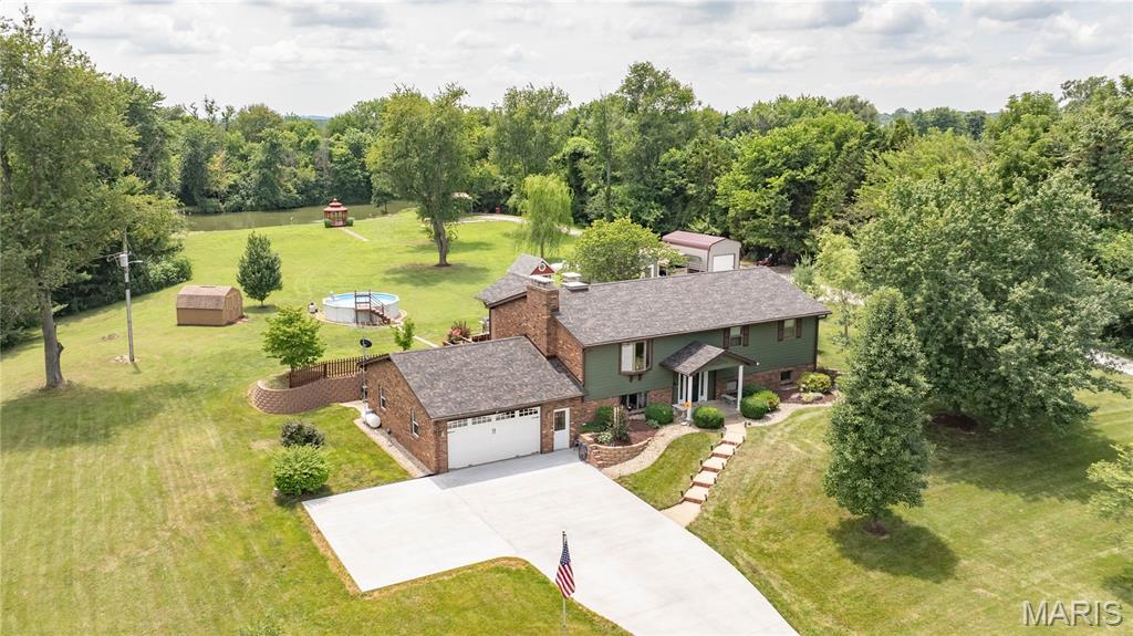 If you’ve been dreaming of peaceful country living without sacrificing convenience, this is the one! Nestled on an incredible 4.5± acre park-like setting just minutes from Jerseyville, Godfrey, and Grafton, this beautifully maintained split-level home offers the perfect combination of privacy, updates, and outdoor enjoyment.
The picturesque property is mostly manicured with partial woods, extensive new landscaping, and a stocked pond complete with an aerator and a beautiful gazebo (approximately 4 years old). Bring your camper, too—220 electric is already in place near the pond, and an extra tall carport in the camper area will stay. A 10-foot Tracker John boat is included, making it easy to enjoy everything this incredible property has to offer.
Inside, you’ll find four bedrooms, three bathrooms, and a versatile lower-level bonus room that’s perfect for a home office, gym, playroom, or hobby space. Beautiful gas fireplace in the living room adds  warmth and charm. Whole house attic fan. Bathroom features whirlpool yub and a retractable shade over the skylight. The spacious kitchen is equipped with a double oven, dishwasher, microwave, trash compactor, and a Jenn Air down and out vent cooktop, as well as a brand new refrigerator, updated tile backsplash, and new faucet. The adjoining sunroom offers year-round enjoyment with its own dedicated A/C unit.
Nearly every corner of this home has been thoughtfully updated. The roof, featuring designer architectural shingles, and new skylights were installed approximately six months ago. Gutter screens on house and sheds. A brand-new concrete driveway was completed just two months ago, while the rear concrete patio (2 yrs old) and deck (constructed with double 2x12 trusses for additional weight load added approximately 6 months ago.) Additional updates include new carpet in the living room and staircase, new laminate flooring in the dining room, and freshly painted throughout. the Andersen windows are a quality feature of the home. Attached two-car garage with a professionally finished epoxy floor and new commercial garage door opener. The garage walks out to back area as well for convenience. 
The lower level is made for entertaining with a one-of-a-kind custom bar crafted from an authentic bowling alley lane, along with a cozy gas fireplace that makes the space especially inviting. Both the wine cooler and mini refrigerator will remain. two spacious bedrooms, laundry and a full bath offer all the soace you need. Outside, you’ll love the new above-ground pool with a Cook portable building for pool storage, a second gravel driveway providing convenient access to the rear of the property and outbuildings, a metal car garage with a rollup door that is only six months old, detached shed with electric, carports for additional covered parking, and the charming, well-equipped “she shed” with gutters and a heat and cooling unit. As a fun finishing touch, the home’s original intercom system is still fully functional!
With countless updates, an unbeatable setting, and a location that’s convenient to everything, this property truly offers the best of country living. Homes with this combination of acreage, amenities, and meticulous care don’t come along often—schedule your private showing today!