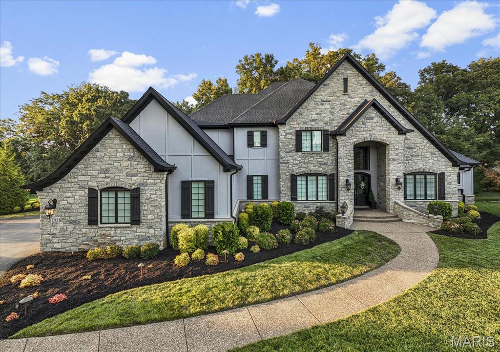 This stunning 1.5-story custom-built home is a truly exceptional find—offering timeless quality and over 7,000 sq ft of luxury living in a private, wooded setting just minutes from Chesterfield Valley. Nestled on 1.25 serene acres in an exclusive enclave, this home blends elegance, warmth, & function.  Step inside and experience the craftsmanship—solid wood floors, rich moldings, & refined finishes throughout. The floor plan features formal living & dining, a soaring 2-story great rm w/ custom fireplace & built-ins, & a fully equipped bar w/ box-beamed ceilings. The luxury kitchen is a chef’s dream, showcasing high-end appliances, custom cabinetry, stone counters, a spacious breakfast nook, and a vaulted hearth room w/ a stone fireplace.The main-floor primary suite is a true retreat, with a spa-like ensuite featuring double vanities w/ stone counters, soaker tub, custom tiled shower, and dual tailored walk-in closets. Upstairs, 3 elegant ensuite bedrooms are joined by a quaint loft—perfect for a reading nook or study space. The LL is ideal for entertaining, w/ a custom bar, family rm w/ stone fireplace, billiards area, 5th bdrm, full bth, and gym space. You'll love the privacy of the wooded backyard w/ an aggregate patio & stone fireplace. The expansive side yard is perfect for play or the future pool of your dreams. An oversized 3-car garage and large laundry/mudroom complete the home. There’s no substitute for quality, and this home proves it at every turn.