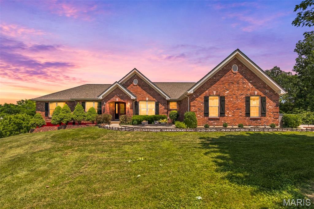 Experience peaceful country living on 5 scenic acres in unincorporated Lincoln County with this stunning waterfront retreat. With timeless curb appeal, the brick-front exterior is complemented by mature landscaping and a beautifully maintained yard that enhances the home’s serene setting. Step inside to find elegant architectural details, including a coffered ceiling in the formal dining room and a vaulted great room anchored by a cozy wood-burning fireplace. A dramatic window wall fills the space with natural light while showcasing peaceful views of the shared 6-acre lake. The spacious eat-in kitchen is designed for both everyday living and entertaining, featuring a center island, marble countertops, and abundant cabinetry, along with convenient main floor laundry nearby. The main level offers three generously sized bedrooms and two full baths, including a private primary suite with a bay window, coffered ceiling, and a well-appointed en suite bath complete with a soaking tub and dual sink vanity. The partially finished walk-out basement expands your living space with a fourth bedroom, full bath, custom bar area, and a large recreation space—perfect for gatherings or relaxing. Step outside to enjoy the covered patio just off the kitchen, an additional patio from the lower level, and a charming gazebo, all ideal for taking in the tranquil surroundings. Additional highlights include a new roof and HVAC system in 2024, making this home as practical as it is beautiful. A rare opportunity to enjoy peaceful, waterfront living with modern comforts and thoughtful updates throughout.