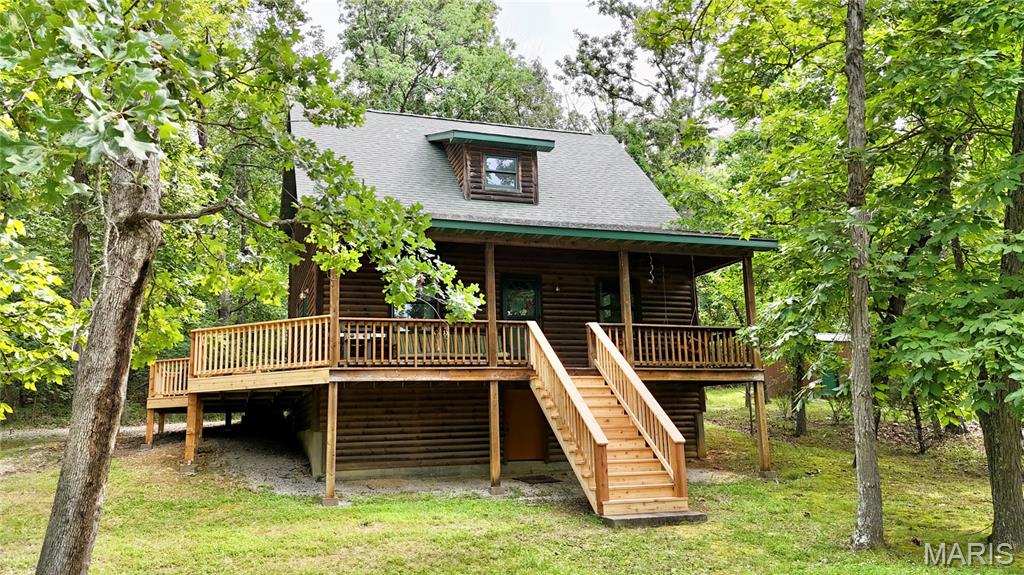 Tucked among the trees on 2.71 acres in the gated Lake Perry community, this inviting 1.5-story log home offers the perfect blend of rustic charm, comfort, and recreation. Built in 2004, this 3-bedroom, 2.5-bath home features 1,632 square feet of warm and welcoming living space designed to embrace its peaceful surroundings. The open-concept living, dining, and kitchen area is highlighted by a soaring vaulted tongue-and-groove ceiling, abundant windows, and a skylight that fills the space with natural light. The spacious kitchen offers an abundance of cabinetry and counter space, a center island for meal prep or gathering, and includes the appliances. The main level also features a comfortable bedroom, full bath, and a convenient laundry area with an adjoining half bath and direct access to the side deck—perfect after a day on the lake. Upstairs, you'll find two additional bedrooms and a recently completed full bath showcasing a beautiful tiled walk-in shower. Step outside to the wrap-around deck and relax while taking in seasonal lake views and the peaceful wooded setting. A partial basement provides valuable storage space for all your lake toys and outdoor gear. The HVAC was replaced in 2026 for added efficiency and improvements have been made to the deck. An added bonus is the inclusion of a second lot, offering exceptional flexibility for the future. Keep it for additional privacy, create extra outdoor space, or explore the possibility of a future homesite. If desired, the additional lot could also be sold separately, providing added investment potential. As part of the desirable Lake Perry community, you'll enjoy access to a 200+ acre lake for boating, fishing, and swimming, along with outstanding amenities including a community pool, picnic areas, playgrounds, and more. Whether you're searching for a full-time residence or a weekend retreat, this property offers the lake lifestyle you've been dreaming of.