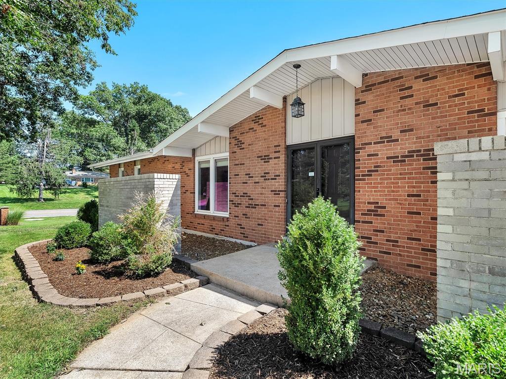 Experience single-level living at 22 La Gorce Drive, a 4-bedroom, 3-bathroom home offering an incredible opportunity under $500K in Chesterfield. The classic brick-front exterior and long concrete driveway create an inviting entrance, framed by a concrete walkway, manicured bushes, and stone-bordered garden beds.

Inside, the huge living room serves as the main focal point of the home, featuring tall, vaulted ceilings with white exposed beams, recessed lighting, warm wood-look flooring, and a forest green accent wall. A long row of windows floods the entire room with natural light and looks out toward the back patio area. The main living zone also includes a built-in wet bar with a railing and stepped-up access.

The kitchen is equipped with white cabinetry, double wall ovens, tile flooring, a beige backsplash, and a separate coffee station setup with open shelving next to a stainless-steel refrigerator. The home offers four bedrooms and three full bathrooms. On the lower level, you'll find a large unfinished basement space set up as a workshop with built-in wooden workbenches and pegboards, along with a separate laundry area featuring a washer, dryer, and utility sink.

Step outside to the private back patio, a spacious concrete courtyard enclosed by white vinyl fencing, complete with a garden bed and sliding glass door access from the house. Offering four bedrooms, three bathrooms, a huge living room, and a private patio, this home delivers space and functionality under $500K in Chesterfield. Welcome home to 22 La Gorce Drive.
