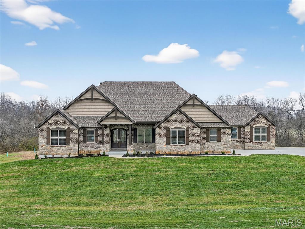 Discover exceptional craftsmanship and refined luxury in this breathtaking 3-bedroom ranch with a dedicated home office, set on 3 private, tree-lined acres. From the moment you enter, the home impresses with soaring vaulted ceilings, designer finishes, and an elegant, open layout built for both daily living and high-end entertaining.
The great room is a true showpiece, featuring expansive windows that frame natural views and a dramatic stone fireplace flanked by custom built-in bookcases. The space flows seamlessly into the gourmet kitchen, where Quartz countertops, a large center island with breakfast bar, and premium stainless steel appliances elevate every meal. A striking stone alcove surrounds the 6-burner gas range, complete with a pot filler. Soft-close drawers, a large walk-in pantry, and a tucked-away planning desk provide exceptional convenience.
A separate formal dining room offers the perfect setting for gatherings and special occasions. Nearby, the drop-zone mud room with cubby bench connects directly to two 2-car garages, including an oversized garage ideal for storage, hobbies, or larger vehicles.
The primary bedroom suite is spacious and serene, highlighted by a tray ceiling and luxurious en-suite bathroom with dual sinks, an impressive seated shower with dual shower heads, and a generous walk-in closet. Two additional bedrooms each offer private bathroom access, creating ideal accommodations for family or guests.
Step outside to your own private retreat: a covered patio with outdoor fireplace, overlooking a large, level, beautifully tree-lined yard—perfectly blending privacy, comfort, and upscale outdoor living.
This extraordinary property offers unmatched style, thoughtful layout, and premium finishes throughout. A rare opportunity for refined living on acreage.