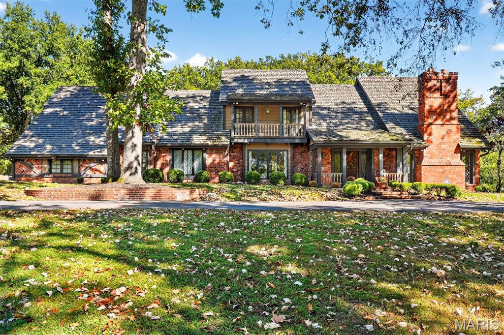 New look! New Price! Nestled in a serene, park-like setting of 3.5+ acres in one of Ladue’s most prestigious neighborhoods, this exquisite Tudor-style residence blends timeless elegance with modern comfort. Surrounded by mature trees and lush landscaping, the property offers a tranquil retreat complete with a saltwater pool, scenic pond, and multiple terraces designed for outdoor enjoyment and entertaining. Inside, classic architectural details abound, including leaded glass windows, parquet flooring, crown molding, and wainscoting. The grand entry welcomes you with a sweeping curved staircase leading to the second floor, setting the tone for the refined spaces beyond. Currently staged as a library, the Living Room's built-in bookcases and gas fireplace with marble surround provide the perfect spot for quiet reading or work. The expansive Family Room, inspired by a ski chalet, is truly a showpiece—featuring a massive stone fireplace as its focal point, a pub-style wet bar, a wall of built-ins, and two sets of French doors opening to a covered terrace that extends the living space outdoors. Ideal for entertaining, the large formal Dining Room is complemented by a spacious modern kitchen with ample room for casual dining and its own gas fireplace, creating a warm and inviting atmosphere. The main level also includes a guest suite that can serve as a second primary or in-law suite, offering flexibility and privacy. Convenience abounds with laundry rooms on both the main and second floors, as well as a perfectly situated second half bath for pool days. Upstairs, the stunning Primary Suite provides a luxurious escape with elegant finishes and serene views of the grounds. A rare combination of character, craftsmanship, and comfort, don't miss this opportunity to make this estate your own private piece of paradise.