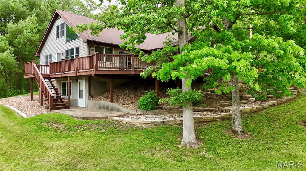This stunning lakefront retreat at Twin Lakes offers the perfect blend of comfort, charm, and unforgettable waterfront views—all tucked within a quaint, private lake community located less than five miles from city limits. Built in 1985, this four bedroom, 2 bath home offers 2413 sf of living area. Designed for both everyday living and weekend escapes, this home welcomes you with an open-concept main level featuring a spacious living room nestled between a dining area and den that is accented by a woodburning soapstone stove, creating warm and inviting gathering spaces year-round. Fresh paint and updated laminate flooring add a modern touch throughout the home. The bright and airy kitchen is beautifully appointed with rich pecan cabinetry, stainless steel appliances including a gas stove with griddle, and a center island ideal for entertaining. The adjoining dining area is surrounded by windows that frame incredible lake and backyard views while providing seamless access to the expansive deck—perfect for relaxing with morning coffee or hosting family and friends. A main level primary bedroom is illuminated with natural sunlight from the many windows that showcase breathtaking lake views and a romantic woodburning fireplace. Solid oak stairs lead to the upper-level loft overlooking the living space, along with a spacious bedroom and additional storage area. The walk-out lower level is home to a secondary primary suite flooded with natural sunlight from oversized windows that showcase breathtaking lake views. Complete with its own private bath and Jacuzzi tub overlooking the water this serene space feels like a private getaway all its own. This space would make a great guest suite as well. Outside, you’ll find beautifully maintained landscaping, a fountain feature, covered swimming dock with ceiling fan, and a unique pull-through garage that can easily double as entertaining space. Whether you’re searching for a full-time residence or the ultimate lakeside retreat, this property delivers lake living at its finest.