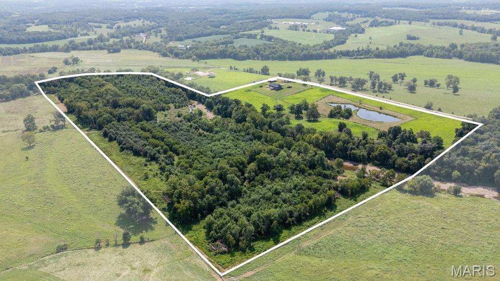 Discover a rare combination of modern comfort, productive acreage, live water, and exceptional privacy with this stunning 58 +/- acre property in Moniteau County. Completed in 2025, the newly built home offers more than 3,300 square feet of finished living space, a large shop, livestock-ready improvements, a stocked pond, and the South Moreau Creek running directly through the property—all while remaining within an easy commute of Eldon, Jefferson City, and Osage Beach.

The main level features 1,889 square feet, 3 bedrooms, and 2.5 bathrooms. At the heart of the home is a spacious kitchen complete with a large island, custom cabinetry, generous pantry, and adjoining utility room. Vaulted ceilings and an open-concept design create a bright, inviting living space. Sliding glass doors open onto the expansive wraparound porch, where panoramic views stretch across the pasture and toward South Moreau Creek—an ideal setting for enjoying quiet mornings or evenings overlooking the property. The finished basement adds approximately 1,500 square feet of living space and includes an additional bedroom and bathroom, office nook, and large living area. One of the home's most unique features is the climate-controlled safe room, providing more than 500 square feet of additional secure space.

Outside, the property is equally impressive. A 32'x50' enclosed shop features concrete floors, power, and a 12-foot overhead door, along with two 14'x50' lean-tos for additional equipment, hay, or livestock storage. Pipe fencing surrounds the shop area, where you'll also find a pipe corral and automatic waterer. The southern portion of the property is fenced and cross-fenced, making it ready for cattle, horses, or other livestock. Just west of the home sits a beautiful pond measuring nearly an acre and stocked with crappie, bass, and catfish. For even more live-water recreation, the South Moreau Creek winds directly through the property. Multiple gravel bars create incredible spots for fishing, swimming, relaxing, or spending summer afternoons with family and friends. Cross the creek to the northern portion of the property and the landscape transitions into a wildlife haven. An established trail system provides access through a diverse mixture of open areas, mature hardwood timber, and walnut groves. This variety creates excellent habitat and cover for deer and turkey, and the seller has enjoyed successful hunts on the property.

Maintain peace and privacy with outstanding accessibility. Located in the Eldon School District, you're approximately 15 minutes from Eldon, 25 minutes from Osage Beach, and 30 minutes from Jefferson City. Call for your showing today!