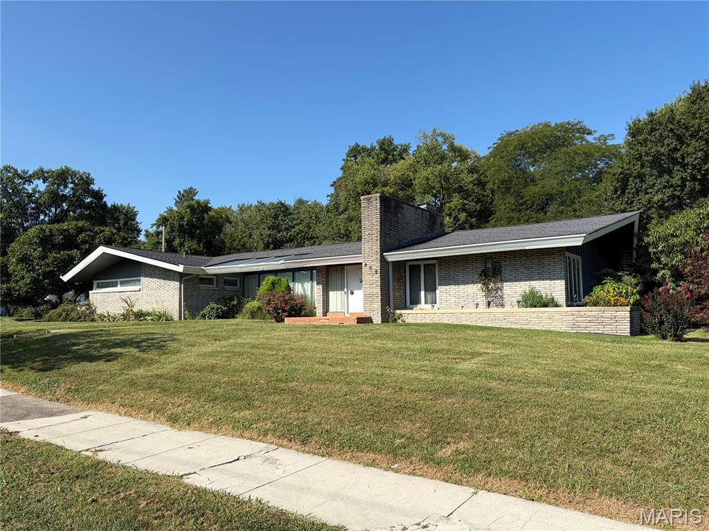 One-of-a-kind mid-century modern home on South Jefferson. This storied home is truly unique — it is a low, linear Contemporary with stacked Roman brick, deep eaves, and a sculptural chimney at the front door. Ribbon windows announce the home's build era the moment you pull up. Inside, original masonry does the talking: floor-to-ceiling Roman-brick walls, a brick-paved hearth with a sleek black stone fireplace, and a built-in window bench made for morning light. A glass-walled sunroom with wood ceiling and green tile floors opens to the patio and lawn — indoor-outdoor living the way mid-century architects intended. The primary bath is a time-capsule pink tile suite; a second period bath and generous sliding-door closets (including cedar) complete the private wing. Kitchen and dining sit on one level with a wall oven and tiled workspace. Full basement for storage and systems. Attached two- car garage, concrete drive, mature trees, garden space, and a greenhouse. Spacious single-level layout with the character buyers cannot get in a new build.
