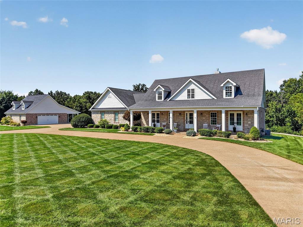 Impressive custom 1.5-story home situated on 5 beautifully landscaped acres, offering 5 bedrooms, 6 baths, a 3-car attached garage, and exceptional indoor and outdoor living spaces. A welcoming hardwood foyer opens to an elegant formal dining room and a striking great room featuring a dimensional ceiling, floor-to-ceiling stone fireplace flanked by built-in bookcases, and an abundance of natural light. The spacious open kitchen is designed for both everyday living and entertaining with Silestone countertops, white Shaker cabinetry, premium stainless steel appliances, and an impressive 8' center island. An adjoining light-filled breakfast room and butler’s pantry provide additional space and functionality. The main-floor primary suite offers a private retreat with a coffered ceiling, generous walk-in closet, and luxurious bath featuring a freestanding soaking tub. Upstairs, a versatile loft area leads to two additional ensuite bedrooms and a bonus loft room, providing plenty of space for family, guests, or a home office. The fully finished walk-out lower level expands the living space with a recreation room, gathering bar, additional bedroom, and full bath. Outdoors, enjoy your own private resort with an inground pool surrounded by stamped concrete, manicured landscaping, spacious areas for entertaining, and a dedicated fire pit area. Completing this exceptional property is a detached 38' x 30' two-car garage featuring private living quarters—ideal for guests, extended family, a home office, or additional recreational space. With 5 acres, multiple living and entertaining areas, and impressive amenities throughout, this one-of-a-kind property offers space, privacy, and versatility inside and out.