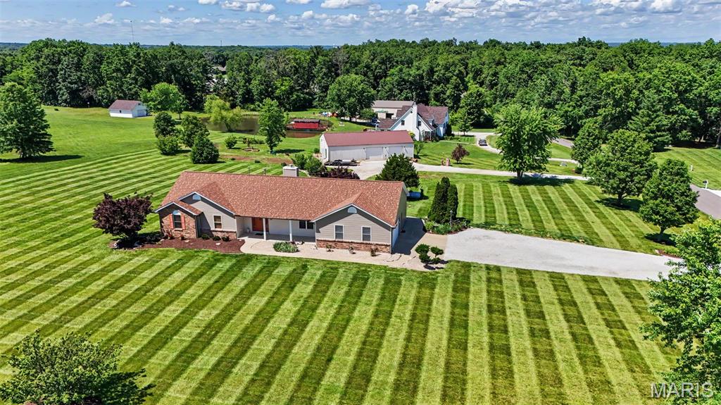 Have you been searching for a property that offers space to breathe, room to grow, and the kind of peaceful country lifestyle that's becoming harder and harder to find? Welcome to 151 Plantation Drive in Troy, Missouri.

Situated on 3 beautifully maintained acres in the desirable Tara Valley subdivision, this custom-built ranch offers over 4,200 square feet of finished living space, a finished walkout lower level, and an impressive 36' x 60' pole barn that opens the door to endless possibilities.

From the moment you arrive, you'll notice something special about this property. The open space, mature landscaping, and meticulously maintained grounds create a setting that feels private, peaceful, and inviting. It's the kind of property where neighbors wave, sunsets become part of your evening routine, and life simply slows down a little.

Inside, the home was designed for comfortable everyday living while providing the flexibility today's buyers are looking for. The vaulted great room features a wood-burning fireplace and serves as the heart of the home, creating a warm gathering space for family and friends. Large windows bring in natural light and offer beautiful views of the surrounding acreage.

The spacious kitchen is built for both function and connection, featuring a breakfast bar, pantry, abundant cabinet space, dining area, and a window overlooking the backyard so you can enjoy the view while preparing meals. Main floor laundry adds convenience to daily life.

The split-bedroom floor plan provides privacy for everyone. The primary suite offers a walk-in closet and private bath with dual sinks, while two additional bedrooms complete the main level.

Downstairs, the finished walkout lower level expands your options dramatically. Whether you need space for entertaining, multi-generational living, guests, hobbies, a home business, or simply room for everyone to spread out, you'll appreciate the massive recreation room with wood stove, full bathroom, two additional sleeping areas, and extensive storage space.

Step outside and you'll quickly understand why the sellers have loved this property for nearly three decades. Enjoy morning coffee on the covered front porch, spend evenings on the expansive deck, relax under the covered patio, or simply take in the peaceful views of open green space and mature landscaping. The property features strawberries, blackberries, grapes, roses, and flowering plants that provide color and beauty throughout much of the year.

For those needing workshop space, storage, hobby space, equipment storage, recreational vehicle parking, or room for a home-based business, the 36' x 60' pole barn is a standout feature. Offering approximately 2,160 square feet, it provides the kind of flexibility and functionality that acreage buyers are actively searching for.

Recent improvements include roof replacement, soffit, fascia, gutters, front porch concrete, kitchen backsplash, well house siding, and a new roof on the pole barn, giving buyers confidence and peace of mind.

Located just minutes from shopping, restaurants, schools, parks, and everyday conveniences while still offering the privacy and open space of country living, this property delivers the best of both worlds.

Homes with acreage, extensive finished living space, a large outbuilding, and this level of care rarely become available. More than just a home, this is a place where memories have been made for nearly 30 years and where the next owners can create a lifetime of their own.

If you've been looking for a property that combines country living, functional space, and lasting value, 151 Plantation Drive deserves a closer look.