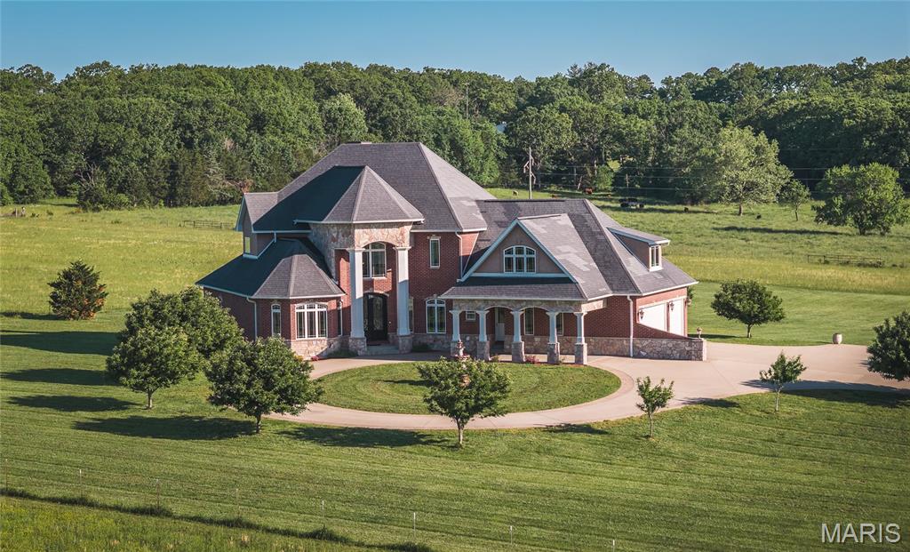 This immaculate, all-brick, custom-built home offers the perfect blend of luxury country living and convenience, situated on 5 +/- stunning acres, only just minutes from town, and boasting 6 spacious bedrooms, four full & two half baths. 
Nearly 7,000 sq ft of exceptional craftsmanship and elegant design await... beginning with the impressive curb appeal featuring a long private asphalt driveway, concrete circle drive with a center fountain, a porte-cochère, and fresh professional landscaping. Step through the grand iron French doors into a breathtaking foyer showcasing a spiral staircase, soaring ceilings, oversized picture windows, and timeless finishes throughout. The formal dining and living room greet you just off the entry, leading into a bright, naturally lit great room, featuring a stunning fireplace and an elegant yet inviting atmosphere. Step out back to the covered concrete patio taking in the natural scenery, or head over to the functional kitchen complete with granite countertops, a large center island, pantry, and built-in oven & microwave. 
Downstairs offers a second living area with a gorgeous fireplace and built-ins, a sauna, fully equipped gym, abundant storage, and more. 
The beautiful brick and stone masonry exterior, added insulation for enhanced climate control, and durable fiberglass matrix shingles further highlight the outstanding quality and style throughout this one-of-a-kind estate. Call today to schedule your private showing!