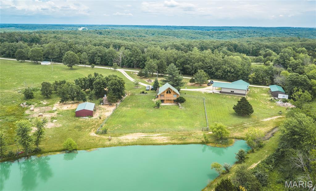 Where History Meets the Horizon — 22+/- Acres | Cuba, MO |  Historic Route 66
Step into a one-of-a-kind Ozark retreat where rustic character runs deep and every detail tells a story. This remarkable log home sits on fully fenced, horse-ready acres in unincorporated Cuba — on Historic Route 66 and less than a mile from Highway 44, offering both seclusion and accessibility that's hard to find.
The cabin-inspired interior welcomes you with an open floor plan anchored by a stunning stone fireplace showcasing an embedded collection of Native American arrowheads and artifacts — a true conversation piece that sets the tone for this extraordinary property. The main floor features the primary bedroom suite, while a loft with a private bedroom and bath adds flexible space above. The walk-out basement rounds out the living quarters with an additional bedroom and full bath, all overlooking a breathtaking 1-acre private lake.
For the hobbyist, tradesman, or entrepreneur, the 2,424 sq ft drive-through workshop and garage is a showstopper — complete with its own bathroom! There is a 4 bay lean-to for equipment storage. Whether you're running a business, housing your collection, or simply need serious workspace, this building delivers.
The unincorporated location bordering Route 66 opens the door to potential commercial use — a rare opportunity for the buyer with vision. Bring your horses, your tools, and your dreams. Want more land, 40 more acres available in the listing #26036315
Acreage | Log Home | Private Lake | Workshop | Route 66 Frontage