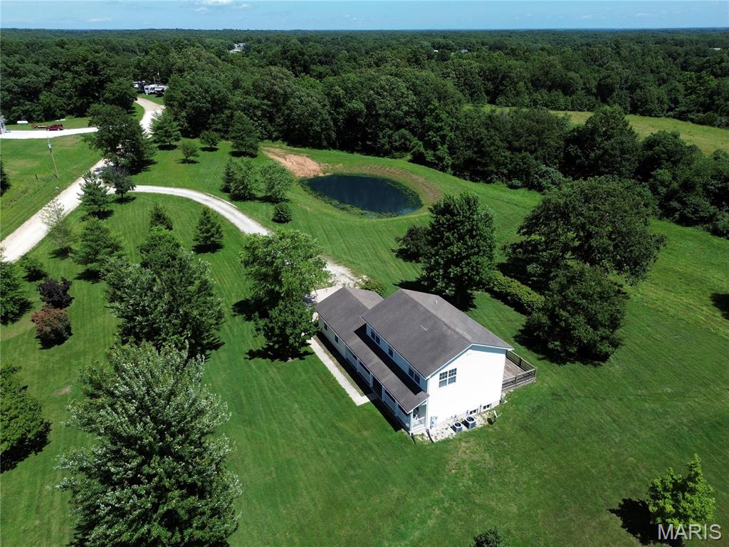 Enjoy peaceful country living with stunning views on 4 acres, complete with a stocked pond and a beautifully maintained home! This move-in ready property offers flexibility with 2 bedrooms and the potential for 3 or even 4 bedrooms by dividing the large upstairs room or enclosing the main-floor room that already features a closet and egress window and 1 & 1/2 baths. The main level includes a spacious living room, formal dining room, main-floor laundry, and a large kitchen/dining area that walks out to an expansive deck and patio spanning the entire back of the home—perfect for entertaining or taking in the scenic surroundings. Upstairs, the primary suite features a separate tub and shower, dual sink space, and ample room to unwind. You'll also find a cozy loft nook, an additional bedroom, and a large walk-in closet. The attached 2-car garage offers convenient exterior access to the patio, while the covered front porch provides the perfect place to relax and visit with family and friends. Bring your chickens, build your dream outbuilding, and enjoy the space and freedom this property offers. Seller will record deed restrictions at closing: no junkyards, no mobile homes, and no swine.