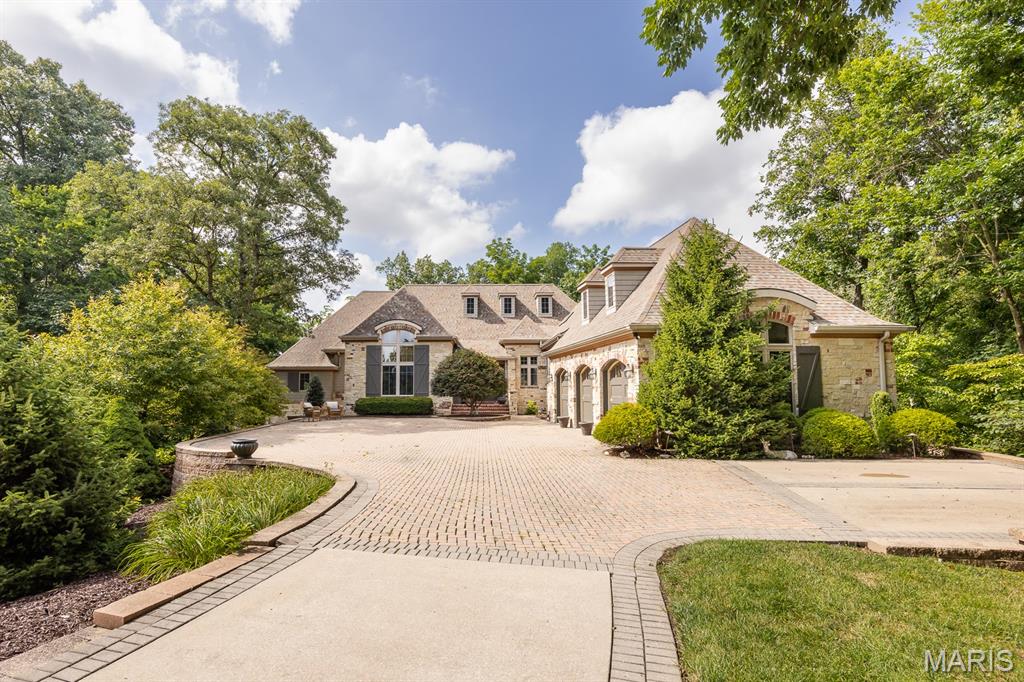 A truly one-of-a-kind, full masonry European-inspired estate, this custom-built masterpiece spans 3.1 acres of wooded paradise—including two additional parcels. Surrounded by mature trees and a picturesque creek, the setting offers unparalleled privacy and tranquility. Inside, exceptional craftsmanship shines through from the antique, repurposed pine floors to the custom ceilings and detailed moldings in every room. Elegant yet inviting, the home features refined finishes and warm, natural textures. The gourmet kitchen impresses with custom maple cabinetry, skylights, and high-end appliances. The sunroom offers serene views of the wooded landscape with oversized windows and access to a private deck. The walkout lower level is designed for entertaining with a large family room, stone fireplace, game and recreation areas, wet bar, four additional bedrooms, three full baths, a second laundry, and abundant storage. Outdoor living is just as impressive with a beautiful stone patio, pergola, outdoor fireplace, and peaceful surroundings. Additional highlights include a new 40-year roof, whole-house generator, natural gas BBQ grill, and three HVAC systems. This is a rare opportunity to own a home that seamlessly blends luxury, comfort, and the beauty of nature. Seller is including 2 additional parcels in the sale of this amazing home.