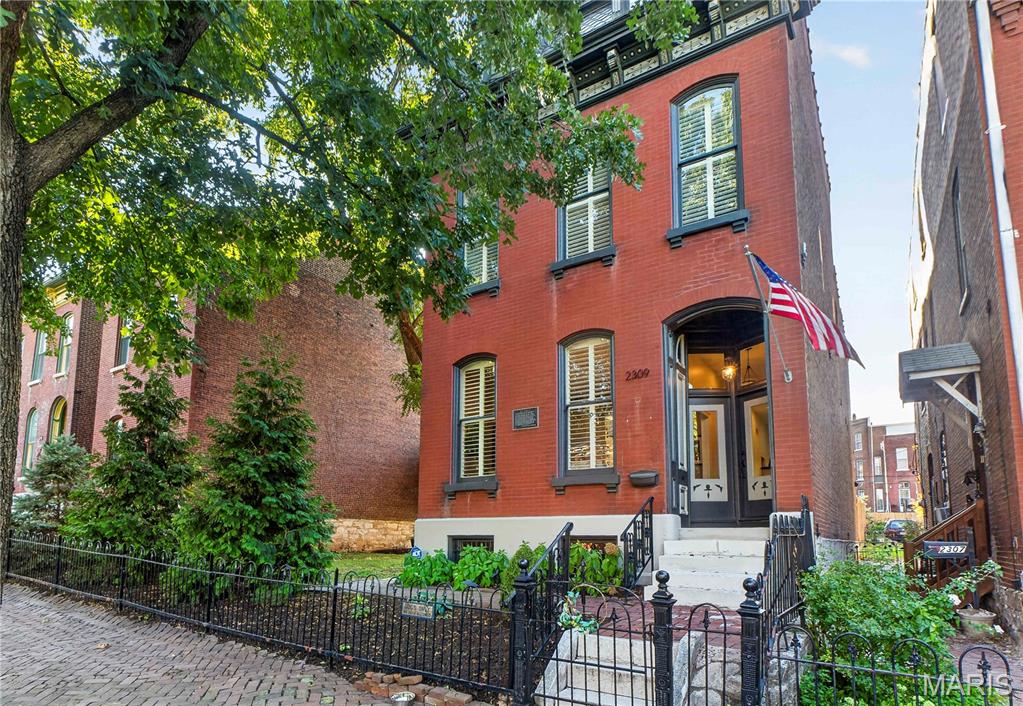 Own a private Soulard retreat. This stately historic home sits on a lush, rare double lot in the heart of one of St. Louis's most storied neighborhoods, with room for a garden, pets to roam, or a future pool. A thoughtfully designed renovation blends historic character with modern updates throughout. The living room's vintage fireplace and original architectural charm flow into a formal dining room. The kitchen boasts Carrara marble countertops, a large central island, and floor-to-ceiling cabinetry, offering an entertainer's hub. Out back, a privacy-fenced yard and oversized garage fit two cars or SUVs plus a golf cart. It's a natural gathering spot for parties, and with Soulard's festivals, farmers market, and restaurants just steps away, plus a short trip to Busch Stadium on game day, you're set for every celebration the neighborhood offers. Upstairs, the primary suite is a quiet escape with a spa-like ensuite bath, double sinks, deep soaking tub, and custom shower. A third-floor guest suite gives visitors their own private space. A rare piece of Soulard history, updated for the way people live today.