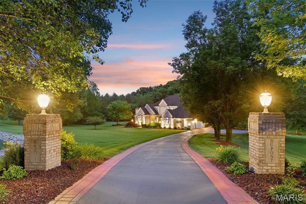 **BUYER FINANCING FELL THROUGH AFTER EXTENSIONS** Commanding **4.53 acres of private, manicured grounds** in one of Belleville’s most coveted enclaves, this remarkable estate at **8501 DuPont Lane** represents a rare convergence of **architectural presence, refined craftsmanship, and serene natural beauty**. Positioned beyond a sweeping drive and framed by mature landscaping, the residence immediately announces itself as a **true trophy property — designed for those who value privacy, space, and distinction.**

Inside, more than **3,500 square feet of thoughtfully curated living space** unfolds beneath soaring ceilings, where **hand-inlaid hardwood floors, intricate millwork, and three fireplaces** create an atmosphere of warmth and quiet sophistication. The grand two-story foyer welcomes guests with a sweeping staircase and cascading natural light, setting a tone of elegance that carries throughout the home’s formal and informal living spaces. 

The **great room** serves as the architectural centerpiece, anchored by an imposing brick fireplace and framed by dramatic vertical space that connects the main level to the upper balcony overlook. Built-in entertainment features, surround sound, and a full wet bar transform the space into an ideal setting for refined entertaining or intimate gatherings.

At the heart of the home, the **chef’s kitchen** balances functionality with style. Custom 42-inch cabinetry with crown molding rises above granite countertops and custom tile work, while premium appliances—including an induction cooktop, wall oven, warmer, and wine cooler—support effortless entertaining. A sun-filled breakfast room wrapped in bay windows offers tranquil views of the estate grounds beyond.

The **main-level primary suite** offers a retreat worthy of a private resort. Beneath a coffered ceiling, hardwood floors lead to a sitting area warmed by a second gas fireplace, while the spa-inspired bath features a soaking tub, separate shower, and dual vanities designed for everyday luxury.

Upstairs, two additional bedrooms—each with walk-in closets and private ensuite baths—provide comfort and privacy for family or guests. A dramatic loft overlooking the great room offers flexible space ideal for a media lounge, game room, or additional living area.

Outdoors, the estate truly reveals its distinction. A **massive composite deck stretches across the rear elevation**, overlooking more than **four acres of peaceful, secluded landscape**. At the center of the grounds lies a **picturesque private pond**—a defining feature of the property and a rare luxury amenity that enhances both the setting and the lifestyle. The home’s automated irrigation system draws directly from the pond, blending elegance with sustainability. 

The walk-out lower level adds tremendous versatility with workshop space, storage, and exceptional mechanical systems including **geothermal HVAC, tankless water heater, private well backup, and numerous structural upgrades**—a testament to the care and investment poured into the home over the years. 

With **five garage spaces, expansive acreage, and a tranquil waterfront setting**, this estate offers a level of privacy and prestige seldom available in the Belleville market.

**Properties of this caliber — combining acreage, water features, and architectural presence — are exceptionally rare.**