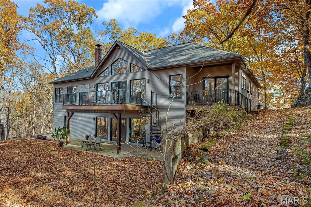 Experience peaceful country living in the Black Forest Subdivision just outside Hermann, MO. This inviting home rests on 24 wooded acres overlooking a stunning valley and offers access to a large shared lake. Designed for comfort and efficiency, the home features 2x6 insulated walls, geothermal HVAC, and underground utilities. Inside, a welcoming foyer opens to a spacious common area connecting the living room, kitchen, and dining area, with breathtaking woodland views. The main level offers convenient living with a master suite, laundry area, and two additional bedrooms, along with an oversized two-car garage for easy entry. The finished lower level includes a family room, two more bedrooms or office spaces, a workshop, and plenty of storage. Wood stoves on both levels provide cozy warmth in winter. Natural landscaping, bluffs, and boulders create a park-like setting where wildlife abounds, your own private forest retreat just minutes from Hermann.