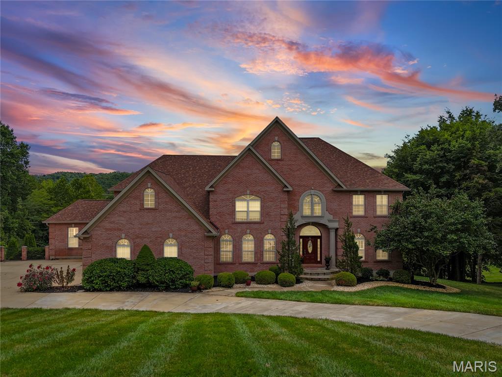 Welcome to luxury living at 10570 Glen Oaks in Festus MO.  This home is situated on over 2 beautiful acres in a desirable location in the sought-after Festus School District!  This spacious home offers a brick exterior with timeless stone detail façade at entry.  Entering the home you are greeted with stunning white marble flooring, high ceilings and a view that spans through to the great room. The great room features built-in library shelving, a gas fireplace, wet bar along with a wall of windows showing natural lighting and serene views. The Main Floor Office is very spacious with Hardwood floors that flow through most of the main level, including the formal dining room that is truly inviting for your guests. After dinner head to the hearth room for an evening coffee or enjoy the 3 season room just off the spacious kitchen having granite counter tops, lots of cabinets, pantry storage, double oven and built in desk space.  There are 2 primary bedrooms, one at main floor making it a nice in-law or guest suite. The other private primary bedroom ensuite is on the upper level.  There are a Total of 6 bedrooms, 6 bathrooms plus 2 Bonus rooms. Upstairs you’ll find 4 generously sized bedrooms having walk in closet systems with 2 connected by a Jack and Jill bath and walk in closets.
The lower level has a full finish that is made for entertainment.  Living room, 2 Bonus rooms, a Gun Safe room and a huge Granite Bar equipped with custom cabinetry, a wine fridge, sink, dishwasher, recessed /bar lighting and full refrigerator. Shoot a game of pool or choose to chill out by the fireplace for a movie night or venture out the L/L French doors to a huge private back patio.  Outside you will find a stunning inground swimming pool featuring diving board and a special treated cool deck system installed to the expansive patio sun deck area surrounding a pristine salt water pool.  You will never be left in the dark in this home with the convenience of a whole home solar system.  This homes setting feels like something special from the moment you pull into the circle drive, so don't miss the opportunity to own such a gorgeous and inviting home.