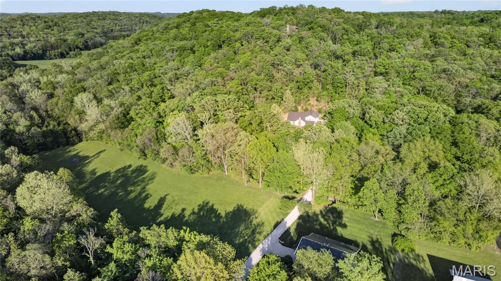 Set on an exceptional 10-acre plot in thriving Labadie perfect for your equestrian estate or hobby farm this is the kind of property that truly stops you in your tracks. Rolling hills, mature trees, green pastures, the prettiest pole barn you’ve ever seen along with a long private drive create a setting that feels like your own secluded retreat, peaceful, scenic, and completely removed yet just a short distance to shopping, dining, and easy highway access. It’s a rare balance of privacy, natural beauty, and everyday convenience that’s nearly impossible to find. Step inside to a thoughtfully designed cottage-style home with an open, connected feel that makes both everyday living and entertaining effortless. The main living spaces flow naturally together, with a vaulted great room anchored by a wood-burning fireplace and large windows that frame the surrounding landscape filling the home with natural light. At the heart of the home, the spacious kitchen opens to the great room and is the perfect place to whip up your favorite meals. Savor chef-worthy appliances: CAFE; Advantium Technology Built-in Wall Oven and Microwave with custom brushed copper hardware, CAFE Energy Star Smart 4-Door French-Door Refrigerator, plus Fisher Paykel double drawer dishwasher.  The main floor primary suite offers a private retreat creating a comfortable and functional everyday escape. Two additional bedrooms upstairs share a full bath, offering flexibility for a variety of living arrangements and a loft to kick-back.  Two main floor work spaces plus a dedicated AT&T fiber optics line makes working from home a cinch. One office opens to the great room with an atrium door to the outdoors.  The other could function as a small bedroom. A laundry/mudroom/ full bath combination provide efficient convenience. The high-pour, walk-out, lower level offers endless possibilities. Whether you envision a home workshop, art studio, media room, game area, home gym, or multiple gathering spaces, the scale and versatility here are hard to find and easy to love. Suffice it to say, the outdoor setting is simply stunning. A fantastic wrap-around deck idyllic for morning coffee and alfresco dining boasts incredible sunset views, over the gently rolling terraced hill of native plants, plenty of perennials and mature trees including Dogwood, Redbud, Ginko, Peach and even Ranier and Bing Cherry! The romantic pole barn with proud cupola on top (1800 SF with 600 SF lean-to constructed in 2022),  adjacent areas suitable for riding ring and paddocks, tree clearing, and thoughtful land enhancements create a setting that is both practical and picturesque. Located in the highly sought-after Washington School district, this property offers the opportunity to enjoy true privacy without sacrificing convenience.  Not to miss! (Please respect the owners privacy. Do not enter the driveway without a confirmed appointment. Thank you.)
