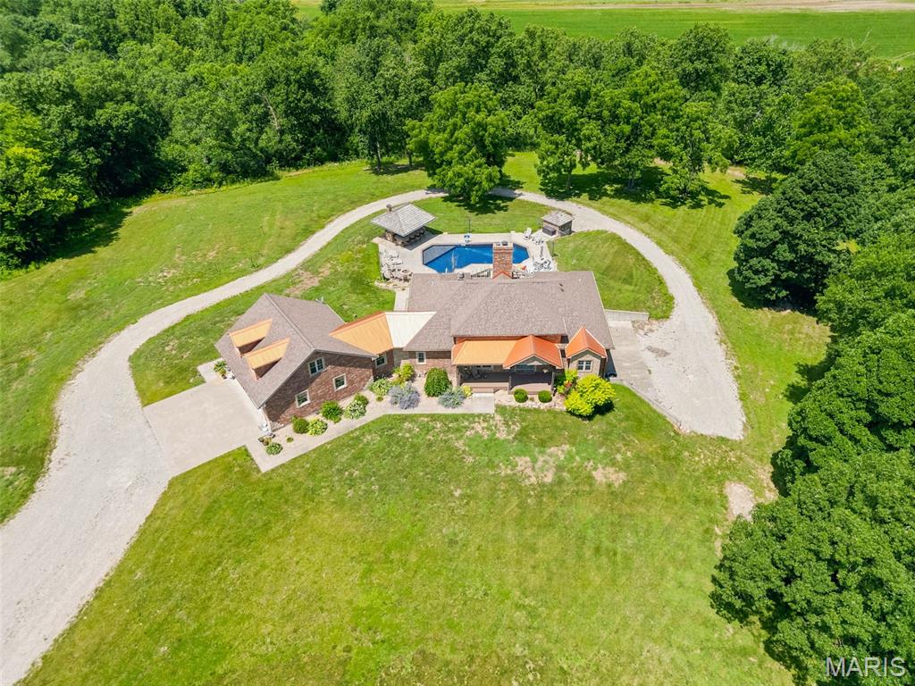 Exceptional in every way! Rustic elegance is what you will find throughout this beautifully designed home on over 63 acres! The pool and "Tiki Bar" overlook an expansive view of the farm fields below... There is a live creek (Dry Fork Creek) that runs almost the entire west edge of the property.  Trails through the woods lead to the creek and the north fields... the north fields are isolated and perfect for sanctuary and food plots if you like to hunt! Tons of Turkey, Whitetail Deer and all other kinds of wildlife call the farm home! Inside you will find a woodburning fireplace in the spacious great room and a Wood Stove downstairs! The Kitchen is a true Cook's Kitchen, and it does not disappoint! The home and the detached garage are full brick and stone, and it is clear that no corners were cut is building this one of kind residence! The home sits back a good distance from the blacktop road, providing privacy & peace and quiet... and views! This place is special! Outside you will find fenced pasture for cattle and two excellent outbuildings that will handle anything you have or can think of! The Detached Garage (The Party Barn) has an entertainment area with another cook station and an awesome walk-in cooler for hanging beef, deer or whatever you like! The Cattle Barn is set up with pens for working cattle, Llamas or whatever your preferred livestock! The creek is full of fish and a great travel corridor for deer! Turkeys love to roost in the big trees overlooking Dry Fork Creek and the occasional Bald Eagle will pay a visit from time to time! This place is special! Come and see your new home today or make it the weekend getaway that everyone will enjoy! Schedule a tour today! Duplicate listing MLS#26041964
