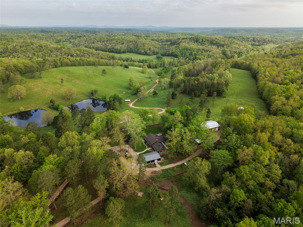 Perched atop an Ozark ridge overlooking a lush, emerald valley, this breathtaking estate at 2937 Wayne Route F represents a masterclass in modern Ozark living and turn-key agricultural engineering. The 2,990-square-foot residence has been completely transformed through a comprehensive renovation, featuring four spacious bedrooms, three full baths, and a designer kitchen anchored by shimmering stone countertops, custom soft-close cabinetry, and a premium gas downdraft cooktop. Below the home, the farm unfolds into a "very clean," high-production livestock operation, featuring intensely managed paddocks of orchard grass, bluegrass, and fescue optimized for rotational grazing. The infrastructure is unmatched, including an automated watering system and valley spigots, robust fencing and cross-fencing, and brand-new livestock structures including specialized cowports. For the professional steward, the property boasts a massive newly constructed 68x48 barn with a 19x22 insulated and cooled office, alongside a new 45x30 garage featuring a 24-foot parking bay, a dedicated mower bay, and over 400 square feet of finished workspace. The land is a recreational sanctuary, bordered on multiple sides by the vast expanse of the Mark Twain National Forest and situated just moments from Lake Wappapello’s Holliday Landing boat ramp via a scenic paved highway. With live water, deep ponds, and permanent hunting blinds already in place, the farm offers easy pursuit of whitetail and turkey. Several historical sites, established garden beds, and high-volume creek crossings add a layer of deep-rooted heritage and utility to this sovereign four-season retreat. From the stunning approach through the forest to the whisper-quiet privacy of the valley, this is a turn-key legacy farm designed for those who demand excellence in both home and habitat. Accessed via private gated drive and approx. 30 minutes North of Poplar Bluff.
