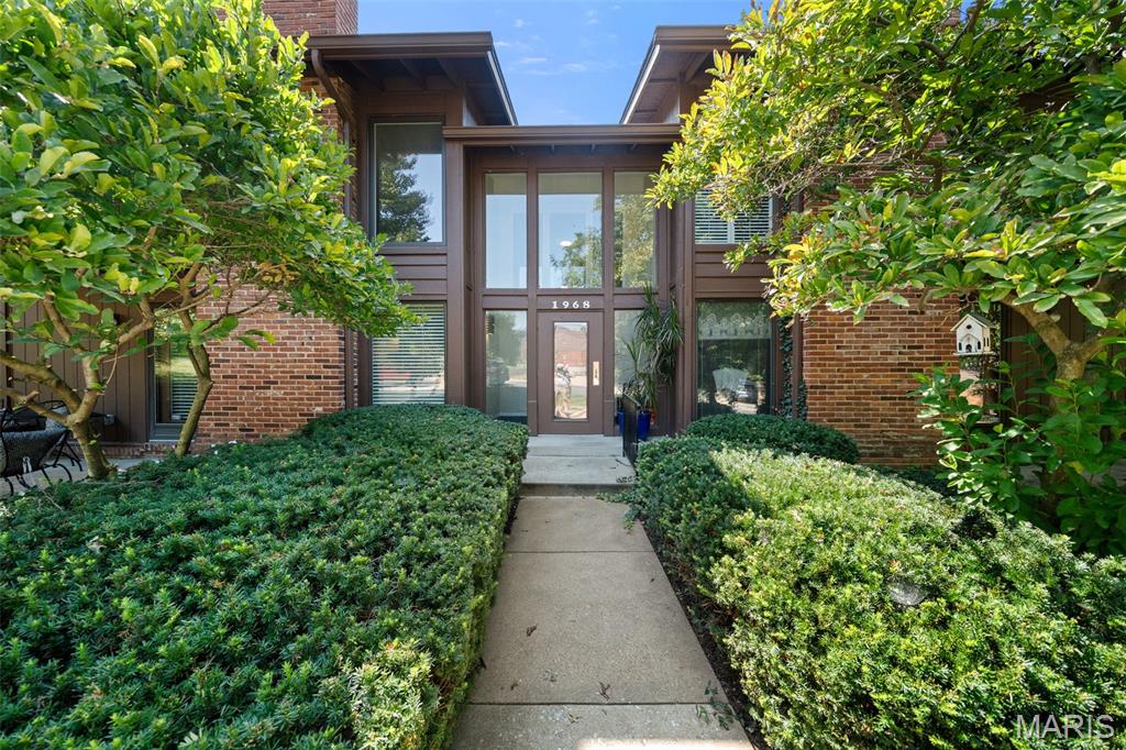 Discover refined, effortless living in this beautifully appointed residence, ideally situated within an inviting, tree-lined community offering an exceptional blend of comfort, elegance, and convenience. From the moment you arrive, manicured garden beds and a secure entry create a welcoming first impression.

Step inside to a spacious, open-concept interior filled with abundant natural light and thoughtfully designed living spaces. The inviting living room is anchored by a handsome brick fireplace, creating a warm and sophisticated focal point. The  door opens to a private deck, providing the perfect setting for morning coffee, evening cocktails, or effortless outdoor entertaining.

The luxurious primary suite is designed as a private retreat, featuring a generous walk-in closet with built-in organizers and a beautifully appointed en-suite bath with an oversized walk-in shower. The spacious second & third bedrooms offer exceptional storage and are conveniently located across from the additional full bath.

The well-designed kitchen offers a functional layout with a convenient pass-through window overlooking the dining area, creating an easy flow for entertaining and everyday living. A private laundry room with a full size washer & dryer adds to the home's thoughtful functionality.

Additional highlights include an attached two-car garage and secure storage area, providing both convenience and peace of mind. Residents enjoy an array of desirable community amenities, including a sparkling swimming pool, tennis courts, and clubhouse, all surrounded by beautifully landscaped, walkable grounds.

Perfectly positioned near West County Mall, area schools, Des Peres Park, premier shopping, dining, hospitals, and everyday conveniences, this exceptional residence offers a sophisticated lifestyle in an enviable location. Beautifully presented and move-in ready, this is an opportunity to enjoy elevated, carefree living in a truly special setting