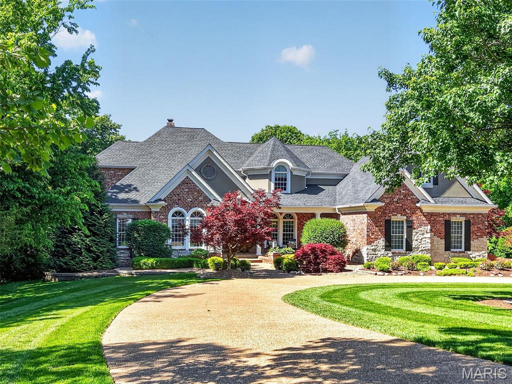 Serenely situated on over 7 breathtaking acres along a privately maintained road in one of the area's most coveted enclaves, this magnificent custom-built estate is designed for the discerning buyer who expects the very best. With over 8,400 square feet of meticulously crafted living space, full brick and stone exterior, and resort-caliber amenities at every turn, this is more than a home, it's a way of life. From the moment you arrive via the sweeping circular drive, the grandeur is undeniable. Inside, soaring ceilings, arched windows, coffered and vaulted details, and an abundance of natural light set the tone for spaces that are as beautiful as they are livable. The heart of the main level is a jaw-dropping two-story great room with a dramatic stone fireplace, wet bar, and a wall of windows that frames the lush, wooded backdrop. The gourmet kitchen is a chef's dream, outfitted with a professional-grade Wolf gas range, built-in Sub-Zero refrigerator, custom soft-close cabinetry, and rich granite counters, centered by a generous breakfast bar island. The adjoining breakfast room and hearth room invite relaxed mornings beneath a stunning wood plank vaulted ceiling & beside a warm gas fireplace. Entertaining is effortless here. A formal dining room with coffered ceiling and butler's pantry & a four-season room overlooking the pool offer spaces for every occasion. A thoughtfully appointed office with French doors and built-in cabinetry is ideal when working from home. The spacious main level primary suite is a true retreat, with a trey ceiling, dual custom organized walk-in closets, and a spa-inspired bath featuring heated tile floors, a freestanding jetted tub, oversized frameless glass steam shower, and two separate vanities. A total of six bedrooms and six bathrooms are distributed across three levels, each designed with comfort and privacy in mind. Upstairs, three generously sized bedrooms each enjoy private bath access and walk-in closets, alongside a dual-desk office and bonus room above the garage. The walk-out lower level extends the living experience further still, with a beautifully finished family room and fireplace, wet bar, recreation room, home gym, private bedroom suite, and an indulgent spa with sauna. Step outside and the estate transforms into a private resort. The gunite saltwater pool features a waterfall and diving board, accompanied by an in-ground spa, basketball court, and a fully equipped pool house with an outdoor kitchen, half bath, and outdoor shower. Beyond the manicured, fully irrigated grounds are peaceful woods that back to Peruque Creek and the Golf Club of Wentzville, offering both privacy and a stunning natural panorama. Six-car garage capacity, multi-unit climate control, multiple water heaters, and every conceivable luxury finish round out an estate that was built with uncompromising attention to detail. This one is special! Don't miss it!