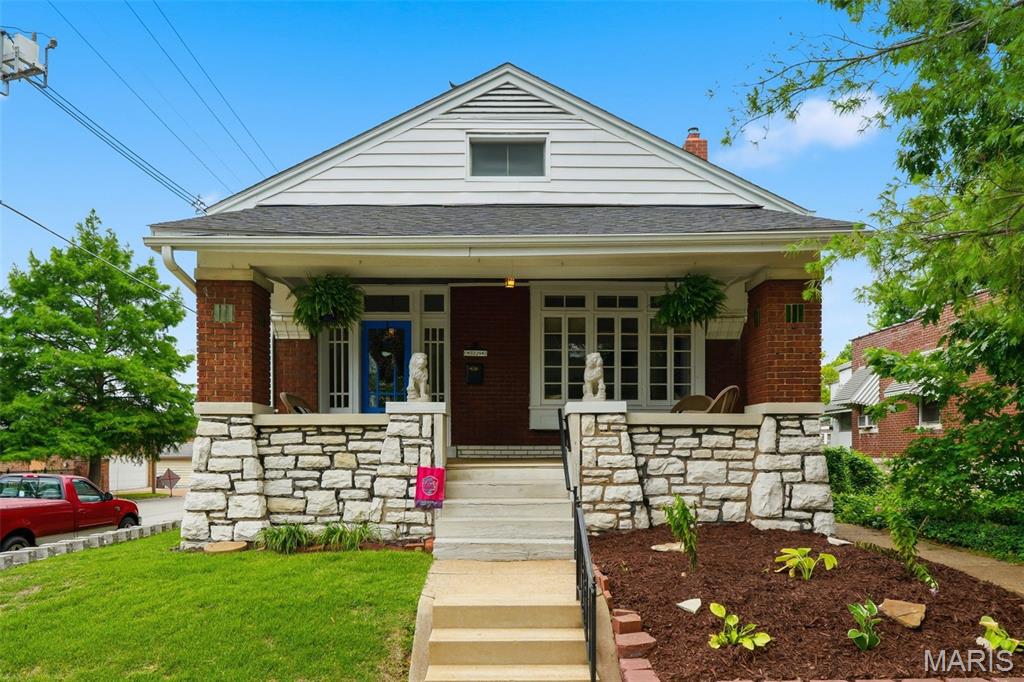 Early twentieth century charm meets modern living in this historic, all brick, arts and crafts bungalow. Undeniable curb appeal is created by the stone accents on the covered front porch. Step through the front door into a generous foyer, unusual in this size home, which is warmed by a gorgeous stained-glass window and dark wood floors. The living room features more stained glass, a window seat, fireplace and custom millwork including leaded glass bookshelves that define the space between living and dining rooms yet still provide flow and an open feeling. The custom millwork continues in the dining room with another window seat, window mullions, beamed ceiling and crystal chandelier. The tiled kitchen features range oven hood and beautiful shaker style cabinets There are two bedrooms, a bright, updated bathroom and a charming sunporch big enough to accommodate TV nights. The basement features two walkouts and is partially finished. Fenced back yard and two car detached garage. New roof in 2025, water heater in 2024, HVAC IN 2021. Walkable to Macklind Business District and a hop, skip and jump from Onesto Pizza and Trattoria.