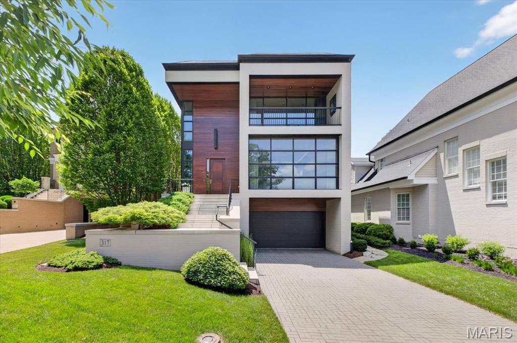 A striking expression of modern architecture, this exceptional residence pairs bold design with a rare sense of warmth and livability. Clean architectural lines, rich wood detailing, curated contemporary finishes, and walls of glass create a home that feels both gallery-like and deeply inviting. A memorable entry introduces the home’s refined architectural language, opening to a stunning main living area anchored by a sleek modern fireplace and expansive windows that draw natural light deep into the interiors. Thoughtfully integrated built-ins provide function with discretion, while shoji-inspired screens offer the option to elegantly separate formal and informal living spaces. At the heart of the home, the kitchen is both beautifully composed and highly functional, featuring streamlined cabinetry, generous stone surfaces, and an oversized island designed for gathering. Open to the dining and family areas, it creates an effortless setting for everyday living, intimate dinners, and elevated entertaining. A sculptural staircase with glass and steel railings serves as one of the home’s defining architectural moments, complemented by a wood-paneled elevator that services all three levels. The primary suite is a serene sanctuary, complete with a sitting area featuring rich leather flooring, a covered balcony, dual walk-in closets, and a spa-inspired bath with a soaking tub, oversized shower, dual vanities, and water closets. Two additional en-suite bedrooms and a versatile gathering space complete the upper level. The finished ground level offers flexibility, with a fourth en-suite bedroom and a spacious recreation room with wet bar, ideal for extended stays, private guest quarters, or relaxed entertaining. A glass-enclosed fitness room, walk-in wine cellar, and spacious laundry room with custom storage further enhance the home’s thoughtful functionality. Outdoors, the property unfolds into a Zen-inspired garden retreat, with curated landscaping, a peaceful water feature, a fire pit, and a fully equipped outdoor entertaining area with a built-in grill and a Big Green Egg - all enclosed by custom iron-and-glass gates. Designed with equal attention to beauty and practicality, the residence also features a heated, level driveway leading to the garage — a rare and highly desirable amenity. Balancing architectural sophistication with comfort, function, and exceptional attention to detail, this one-of-a-kind residence offers a rare opportunity to experience contemporary luxury living at its finest.
