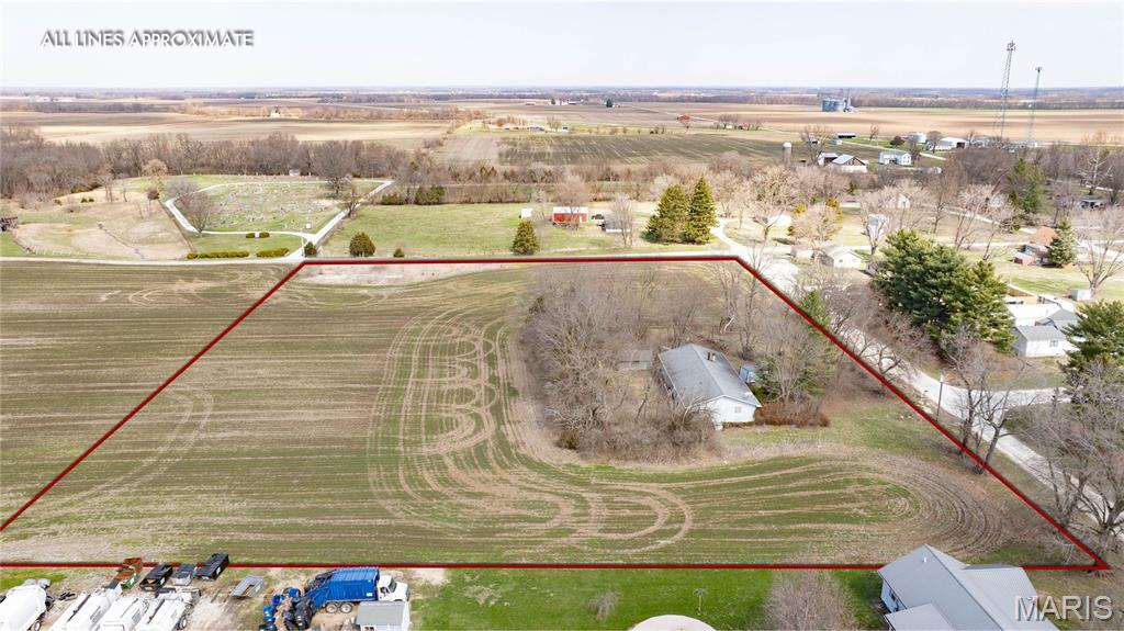 This 4.75 +/- acre corner property offers a versatile mix of usable land and functional improvements. Much of the acreage is tillable, making it well suited for agricultural use. The north side of the property includes a concrete pad with water, septic, and electric hookup, as well as a storm shelter, providing valuable infrastructure for a trailer, guest setup, or expansion.
The residential structure is accessed by a gravel driveway and features an attached two-car garage and a chain-link fenced yard. Inside, the main level includes a spacious living room with a fireplace, a combined kitchen, dining, and laundry area.
The main floor also includes a primary bedroom with an en-suite bathroom and shower, a full bathroom and two secondary bedrooms. The full, unfinished lower level spans the footprint of the home and offers significant storage or future finishing potential, with additional laundry hookups.
With acreage, existing utilities, and multiple options for use and improvement, this property offers a strong opportunity for buyers seeking to make a space their own with flexibility and long-term potential. 
NOTE: The neighboring farmer will retain the right to farm the property for the 2026 crop year under an existing agreement with the seller. Possession for farming purposes will transfer to the buyer following the 2026 season, at which time the buyer may utilize the property as they see fit.
