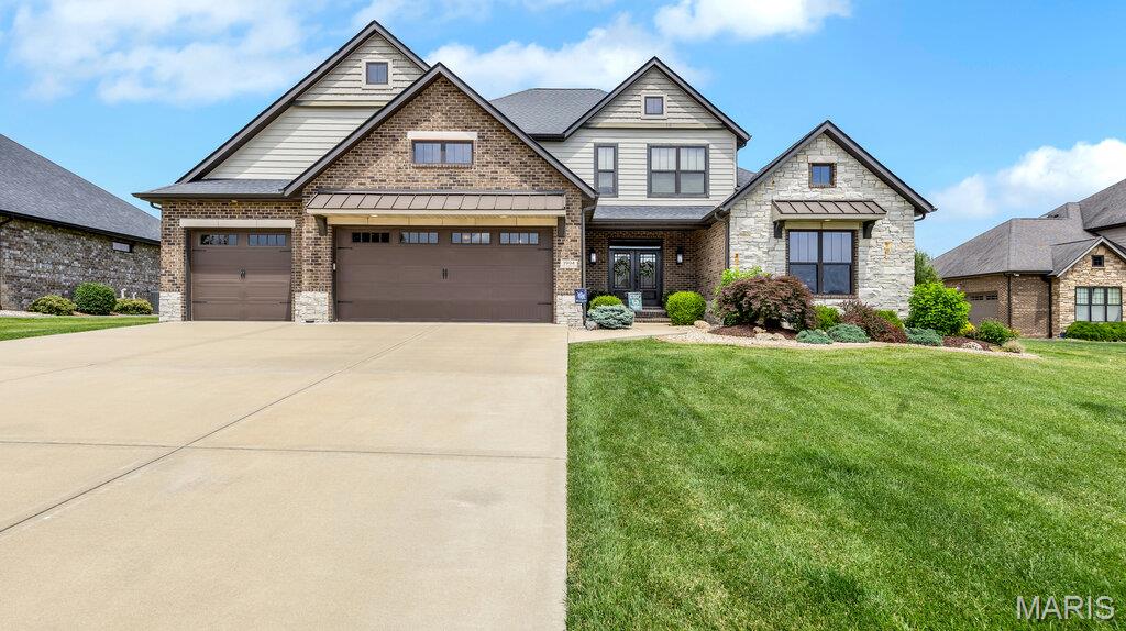 Welcome to a home where luxury, craftsmanship, and thoughtful design come together on a spectacular half-acre-plus homesite in one of Edwardsville's most sought-after communities - Stone Cliff Manor. Offering 6 bedrooms, 5 bathrooms, and exceptional indoor and outdoor living spaces, this stunning residence delivers the perfect blend of sophistication, comfort, and functionality.
From the moment you enter, the grand foyer impresses with gleaming hardwood floors, handcrafted floating wood shelves, and striking architectural details. An open staircase creates a dramatic focal point, while expansive views into the great room showcase plentiful natural light, rich millwork, and refined finishes throughout. The great room is anchored by a floor-to-ceiling stone fireplace flanked with tailor-made shelving and enhanced by an elegant tray ceiling.
The chef-inspired kitchen is designed for both everyday living and entertaining, featuring solid surface countertops, generous cabinetry, designer finishes, a stylish backsplash, and ample prep space. The open-concept layout flows seamlessly into the dining and living areas, creating an ideal setting for everything from casual family meals to holiday celebrations.
The luxurious main-level primary suite serves as a private retreat with a spa-inspired bath featuring a soaking tub, separate tiled shower, and a spacious walk-in closet complete with tailored organization and a dresser integrated into the design. Four secondary bedrooms each offer their own private ensuite bath, providing comfort and privacy for family and guests. A convenient laundry room and sizable drop zone complete the main level.
The finished lower level expands the home's versatility with a spacious recreation area, a contemporary wet bar featuring granite countertops, a guest bedroom suite and generous storage space—making it ideal for entertaining, overnight visitors, or multi-generational living. Thoughtfully equipped for long-term comfort and peace of mind, the home also includes a passive radon mitigation system, waterflow backup system, hardwired Cat-5 connectivity throughout, dual 200-amp electrical panels, and two 50-gallon gas water heaters. 
Outdoor living is equally remarkable. A covered patio overlooks the beautifully landscaped backyard, complete with an irrigation system, mature trees and flowers, dedicated garden area, and a firepit retreat. Whether hosting friends or enjoying a quiet evening outdoors, this backyard offers the perfect escape.
The attached 3-car garage has been thoughtfully designed with an epoxy-coated floor, precision-crafted cabinetry with double-bypass wooden barn doors, a workshop bench, dedicated storage closet, and additional windows filling the space with natural light.
Residents of Stone Cliff Manor enjoy illuminated boulevards, luxury homesites, a scenic pond, meticulously maintained common area and a community pavilion. Located within the highly acclaimed Edwardsville School District, this exceptional property is just minutes from schools, shopping, dining, recreation, and downtown Edwardsville, with convenient access to St. Louis.
Distinctive architecture, exceptional amenities, refined finishes, and a premier location make this remarkable home a rare opportunity in one of Edwardsville's finest neighborhoods.