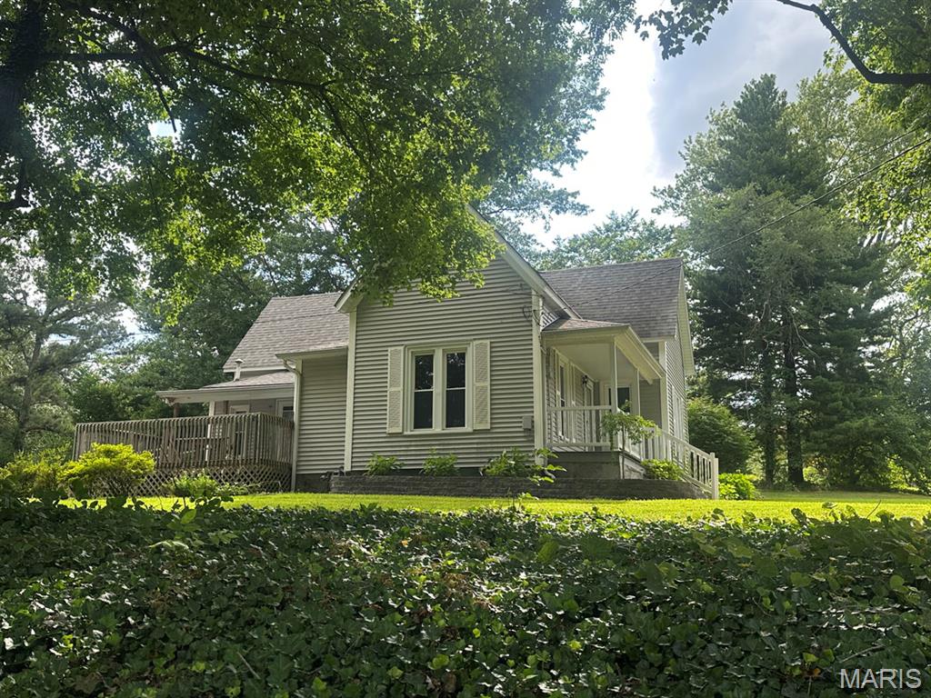 Charming Victorian home built in 1897 offering 1,836 sq. ft. of updated living space. Perched on a hill, the property features beautiful 2025 landscaping with flower beds, dogwood trees, additional plantings, and an irrigation system. A welcoming covered front porch leads to an open floor plan with a living room featuring a corner gas-log fireplace, dining room with built-ins, full bath, and two main-floor bedrooms with generous closets. Upstairs includes a carpeted bedroom, window A/C, and extra space for storage or future use. The remodeled kitchen (2013) boasts custom cabinetry, quartz countertops, breakfast bar with seating, stainless appliances, and wall-mounted TV. Additional updates include roof (approx. 2011), LeafFilter gutter protection (2021), foam insulation, and dehumidifier (2021). Detached garage offers heat, window A/C, side shed, and half bath. A rare blend of historic charm and modern convenience.