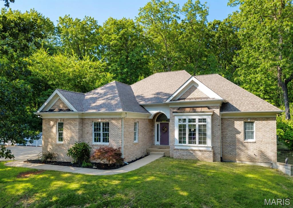 Tucked into a heavily wooded 1.21-acre setting, this impressive 3-bedroom, 4-bath home offers approximately 3,134 square feet of finished living space and a rare combination of privacy, upscale finishes, and convenient access. A long driveway leads up to the residence, providing ample concrete parking and an attached two-car garage. Inside, the main level features soaring 12-foot ceilings, crown molding, and a beautiful remodeled kitchen with upgraded countertops, double ovens, under-cabinet lighting, and a subway tile backsplash. The adjoining hearth room is anchored by a striking Colorado stone fireplace. The spacious primary suite features a sculpted tray ceiling and a large bathroom with dual sinks, a separate shower, and a Jacuzzi tub. Main-floor laundry adds everyday convenience. The finished walkout basement offers 9-foot ceilings, stamped concrete floors, a large recreation room, full bathroom, and generous storage space. Outside, enjoy both covered and open patios, an expansive backyard with a retaining wall, and views of nearby Birch Creek Golf Course from the walkout patio. Public water and sewer—all less than five minutes from I-44!