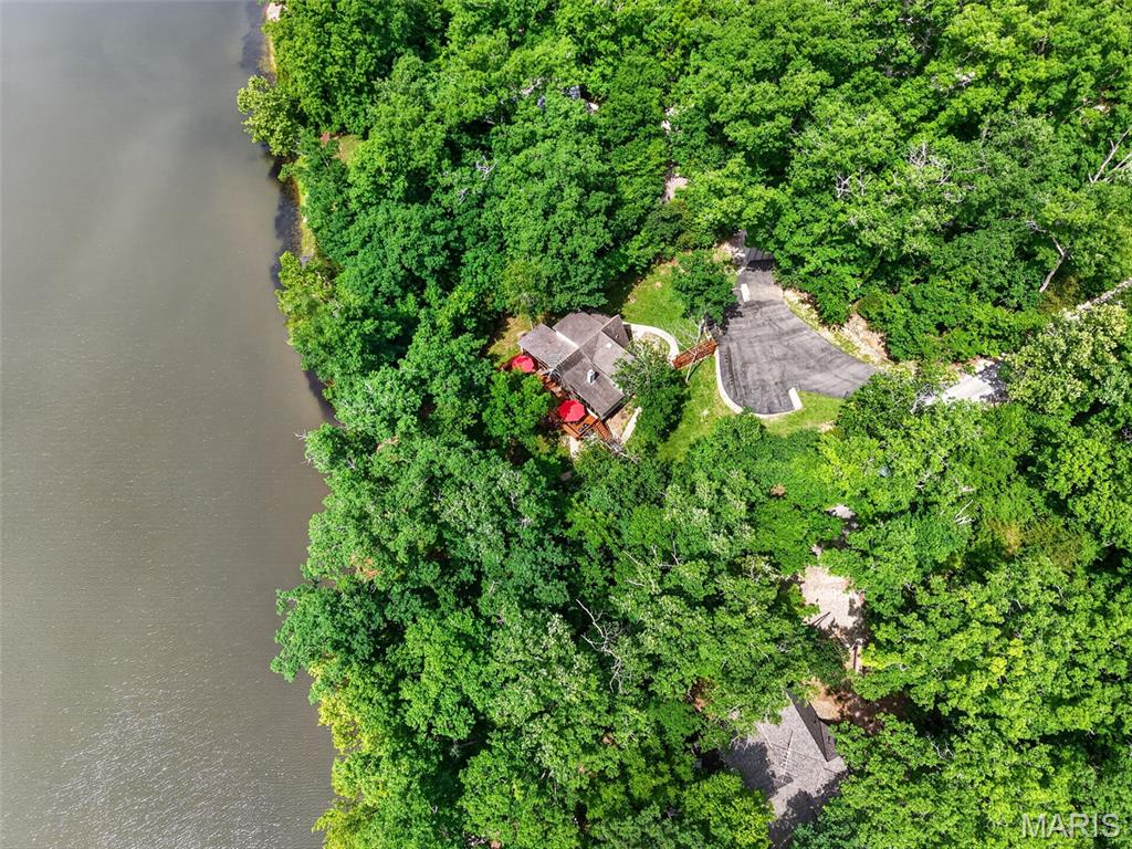 Perfectly located on the shores of Whitetail Lake, this beautifully maintained Santa Barbara-style chalet offers breathtaking views from the moment you pull down the paved driveway. A gorgeous stone retaining wall, paved parking area, and paved driveway create exceptional curb appeal and welcome you to this exceptional waterfront retreat. Attractive exposed aggregate walkways lead to the front porch and continue from the deck steps down to the private dock, adding both beauty and functionality to the outdoor living spaces. Situated on over an acre, the property enjoys a spacious setting and is conveniently located near the golf course, Lake Aspen Beach, and the boat launch.
Featuring three bedrooms, two full baths, an enlarged kitchen, expanded great room, and a glass-enclosed sunroom, this chalet has been thoughtfully updated for comfortable lake living. The stunning setting is complemented by a large expanded deck, perfect for relaxing or entertaining while enjoying the view.
A storage shed provides plenty of room for all your lake toys and equipment. Best of all, the property is being offered fully furnished and includes boats under chalet, making it truly move-in ready and ready to enjoy from day one.  This is a rare opportunity to own a fully furnished waterfront retreat in one of Innsbrook’s most desirable locations. Polaris available separate from the sale of chalet