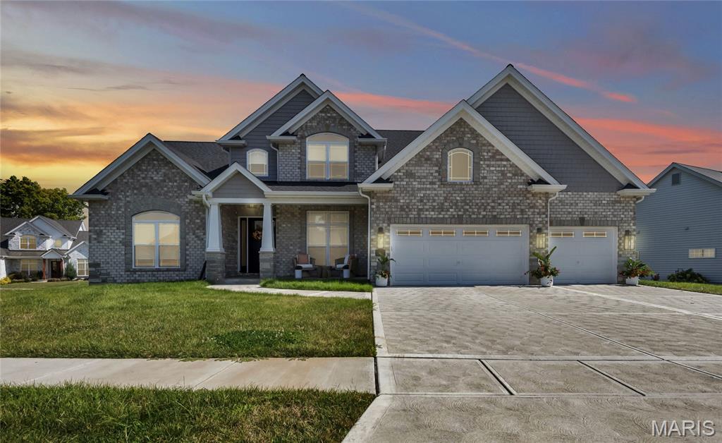 Modern, and nearly new, Custom Home in an exclusive St. Charles neighborhood set located in a quiet private subdivision of just 30 homes. Just minutes to downtown St. Charles, Boeing, Amazon headquarters and STL airport. This grand home built in 2023 by an esteemed custom home builder that only builds in small select communities. The bright, open main level features soaring ceilings, a see-thru stone fireplace, 8' doors, and a wall of transom windows with remote-controlled shades. Wide-plank engineered wood floors lead past the formal dining room with a coffered ceiling into the high-end kitchen. The kitchen is equipped with a massive quartz island, staggered white cabinets, a porcelain backsplash, undercount lighting and two-tone stainless appliances (including a 6-burner gas cooktop). A walk-in pantry and a dedicated beverage station with a wine fridge make entertaining a breeze. Nearby, a large mudroom off the 3-car garage includes a utility sink, bench, and coat rack. Primary bedroom on main level has coffered ceiling, palladium window, gorgeous bath w/floor to ceiling tiled shower w/rain shower head, soaking tub, dbl vanities, natural stone flooring and 2 closets. Upstairs, a large bonus room anchors three additional bedrooms—all with walk-in closets. Two bedrooms have private en-suite baths, and one connects to a Jack-and-Jill bath shared with bonus room.
Relax on the covered back patio, which features a see-through gas fireplace perfect for watching the game outside. The property also includes a full lawn sprinkler system, dual-zone HVAC, and a deep 9-foot pour basement with a plumbing rough-in, ready for your finishing touches